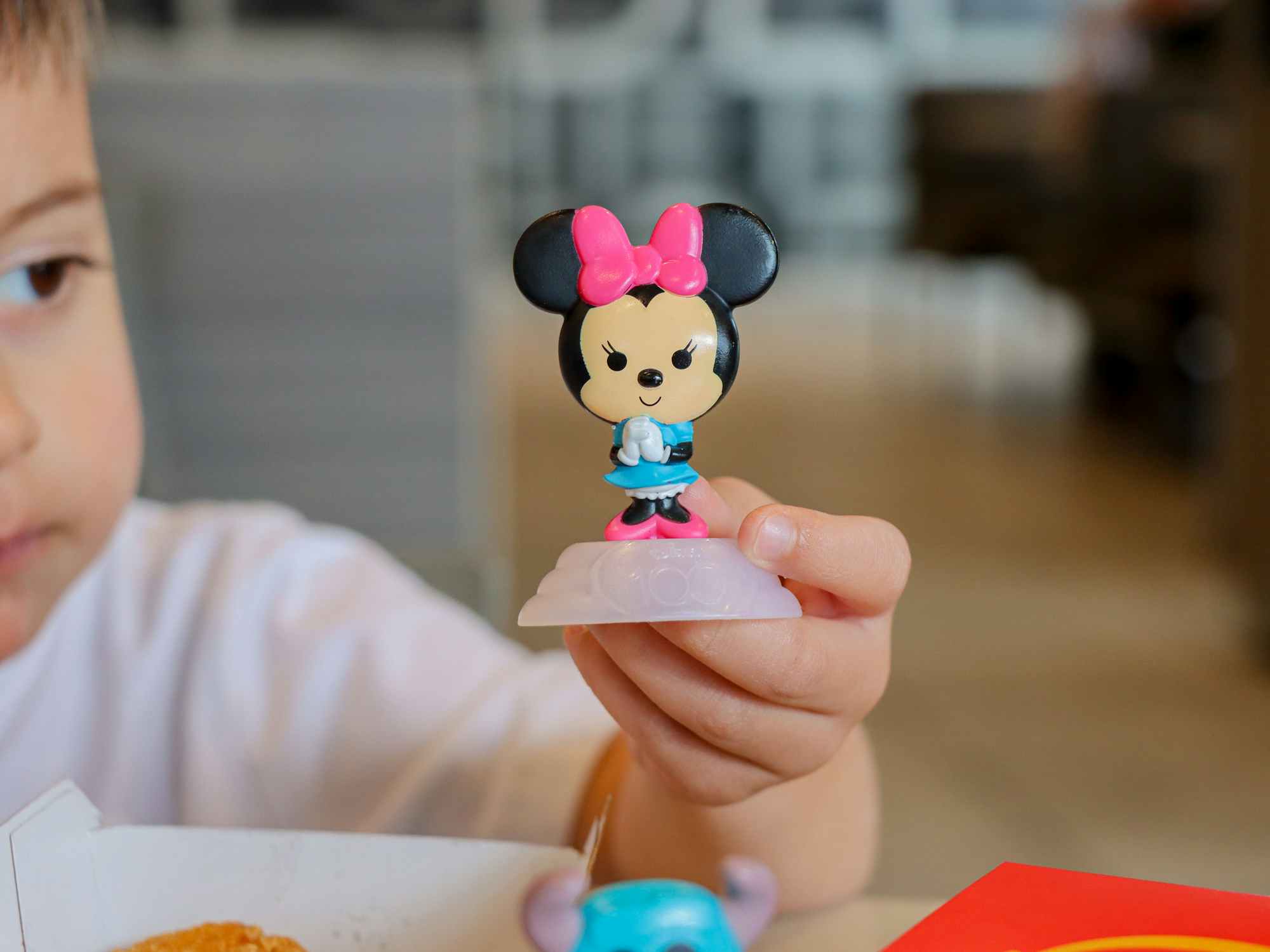 a child holding up a disney happy meal mcdonalds toy
