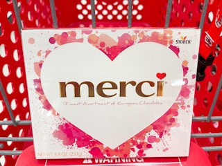 A Merci assorted chocolates box sitting in a store cart.