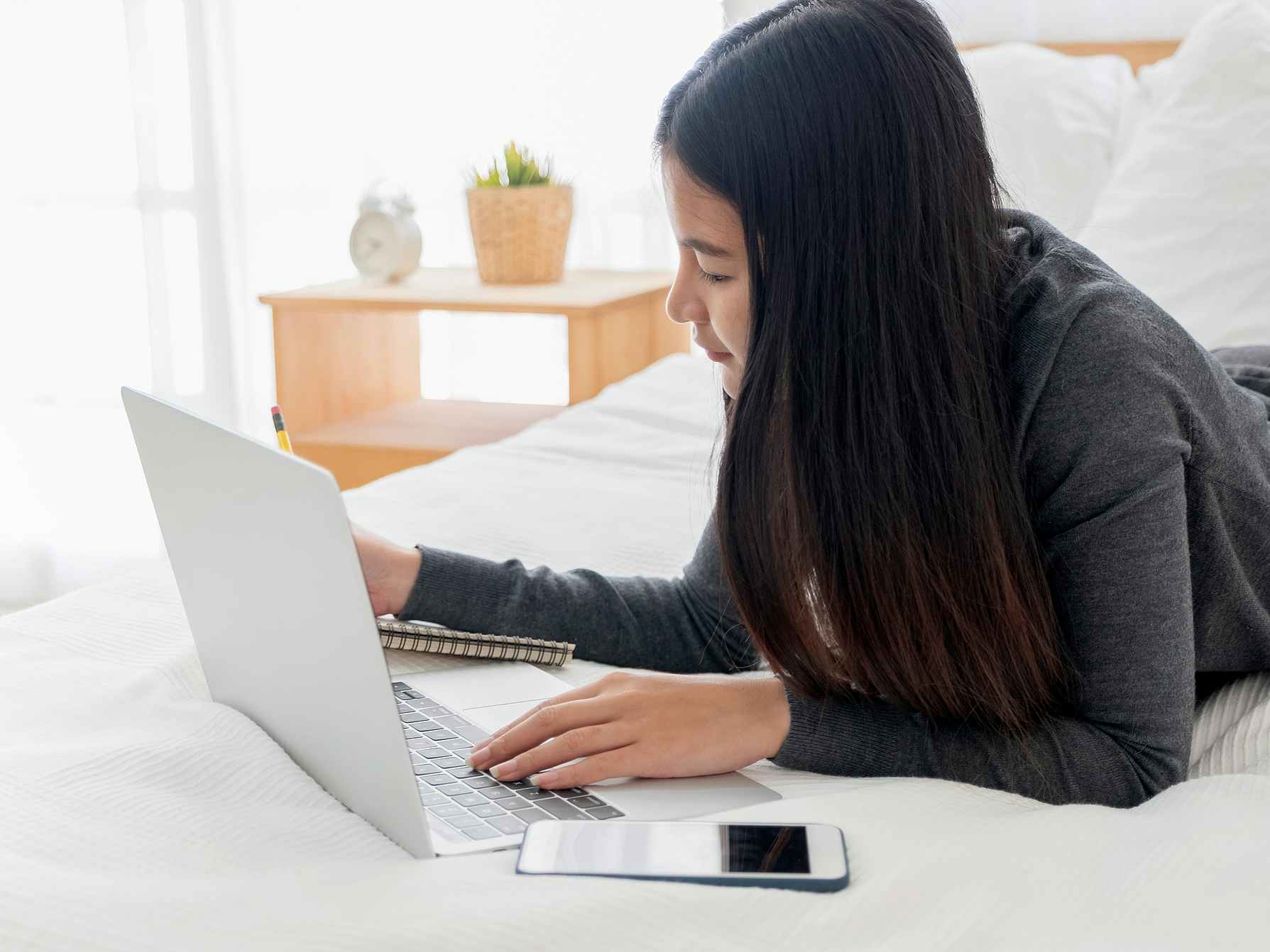 person on bed working on laptop