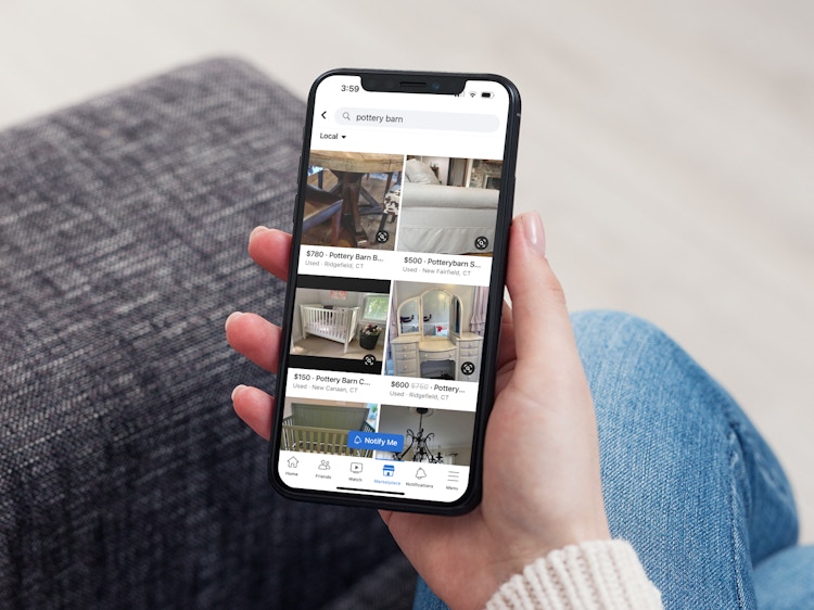 A woman sitting on the couch holding her phone and looking at Pottery Barn items on Facebook Marketplace
