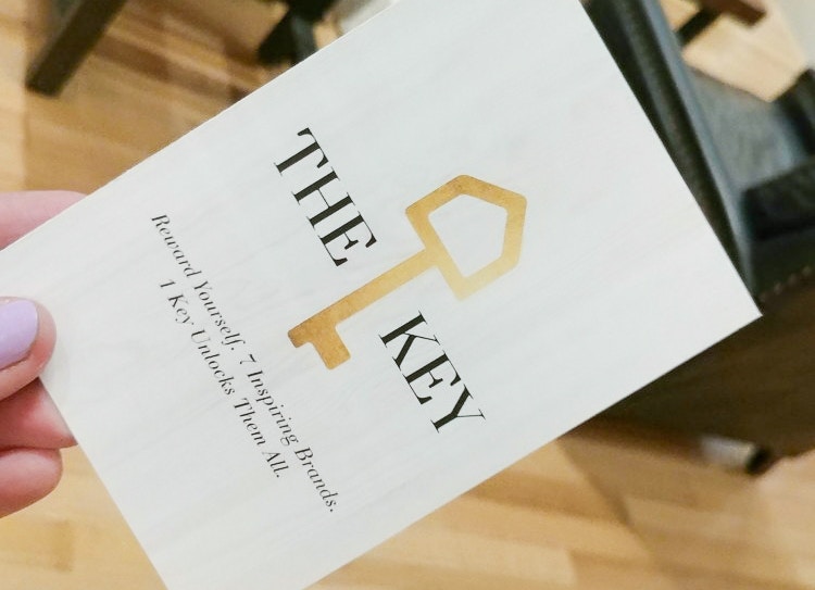 A woman's hand holding a brochure for the Pottery Barn Key Rewards program