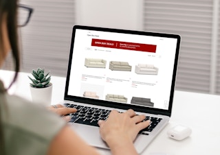 A woman on her laptop looking at discounted Open Box items on PotteryBarn.com