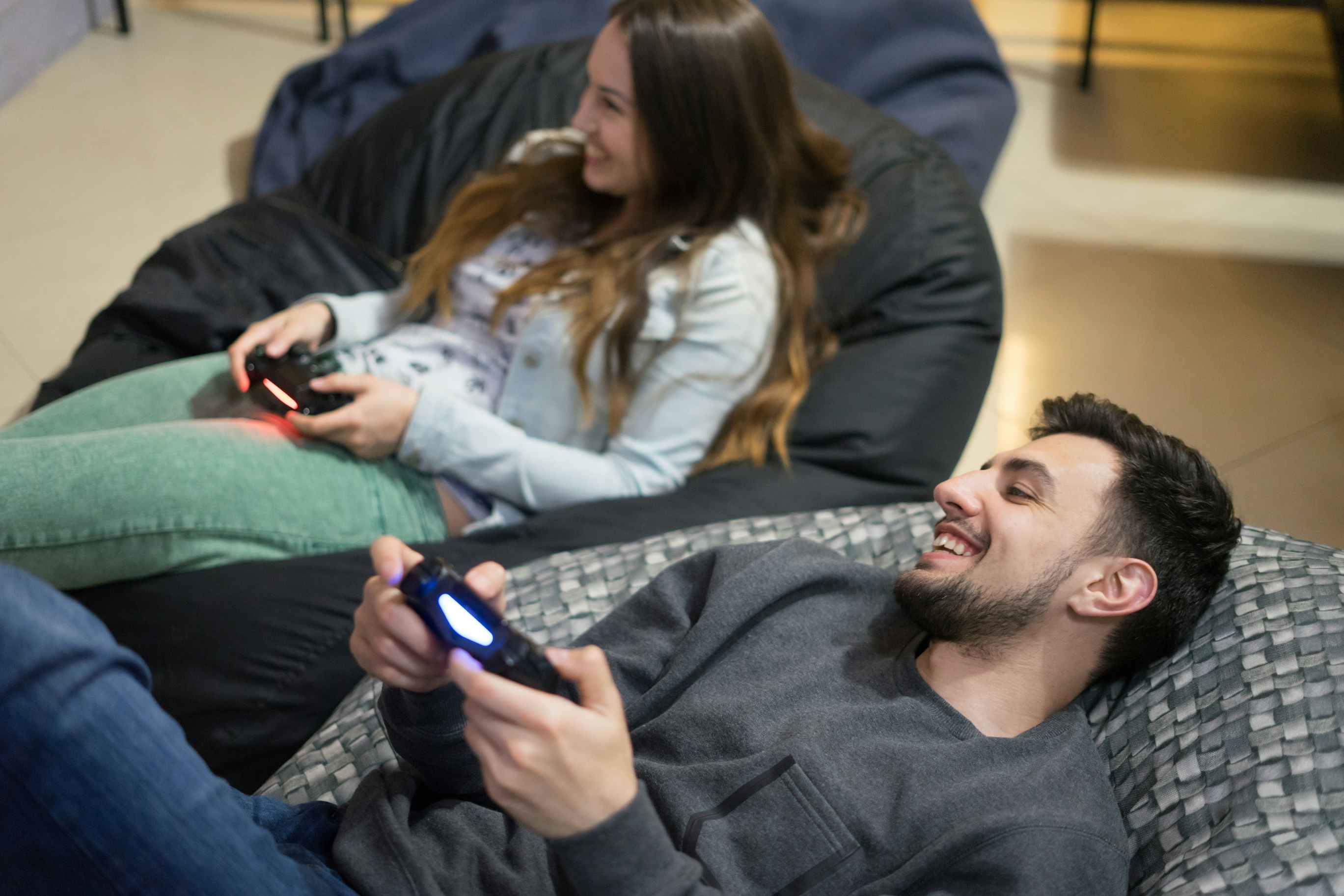 A couple sitting on bean bag chairs playing a video game together