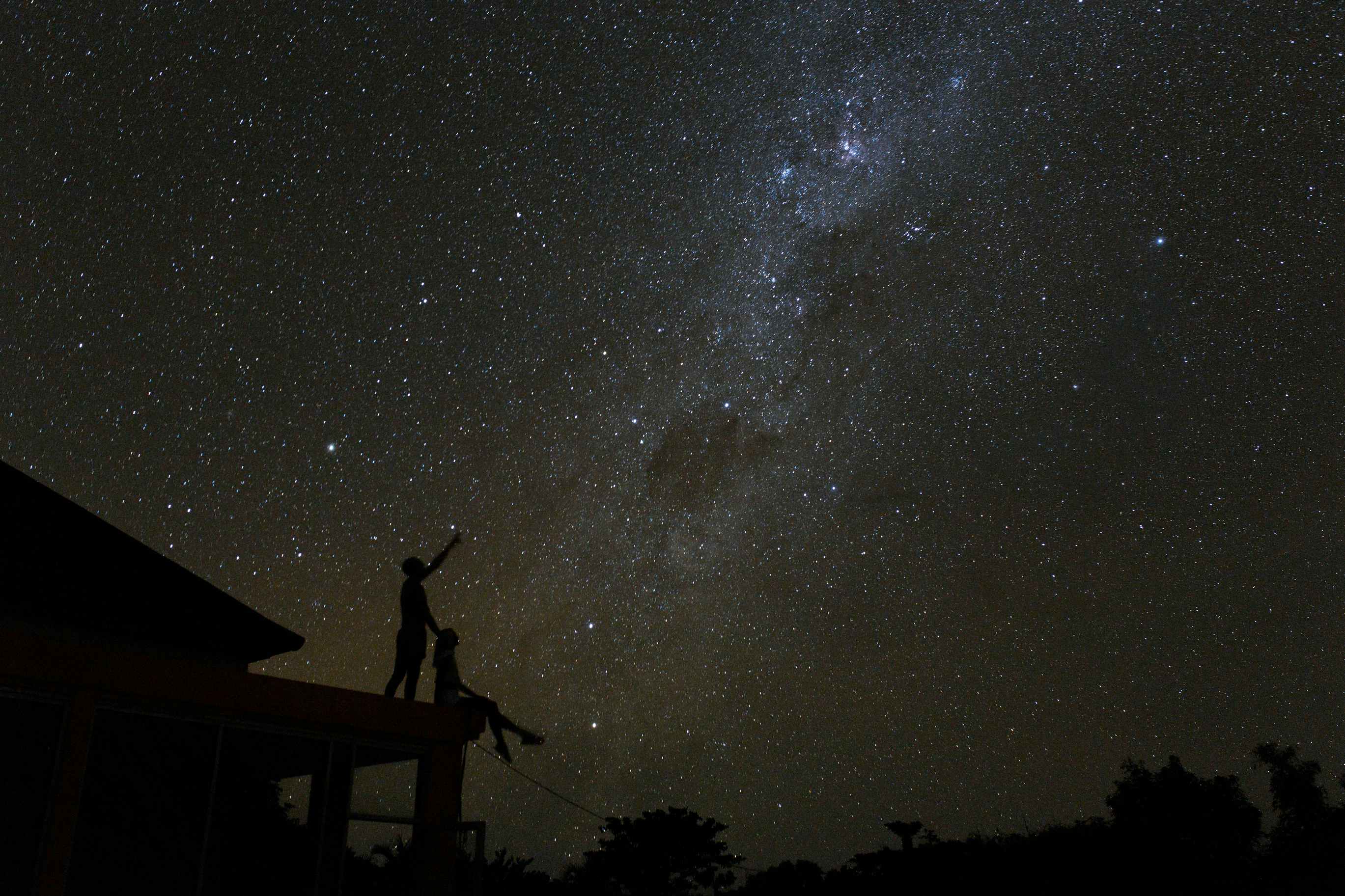 Two people together on a roof looking at stars