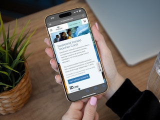 Someone holding a cell phone displaying the Sea World Orlando webpage about the Teacher Pass