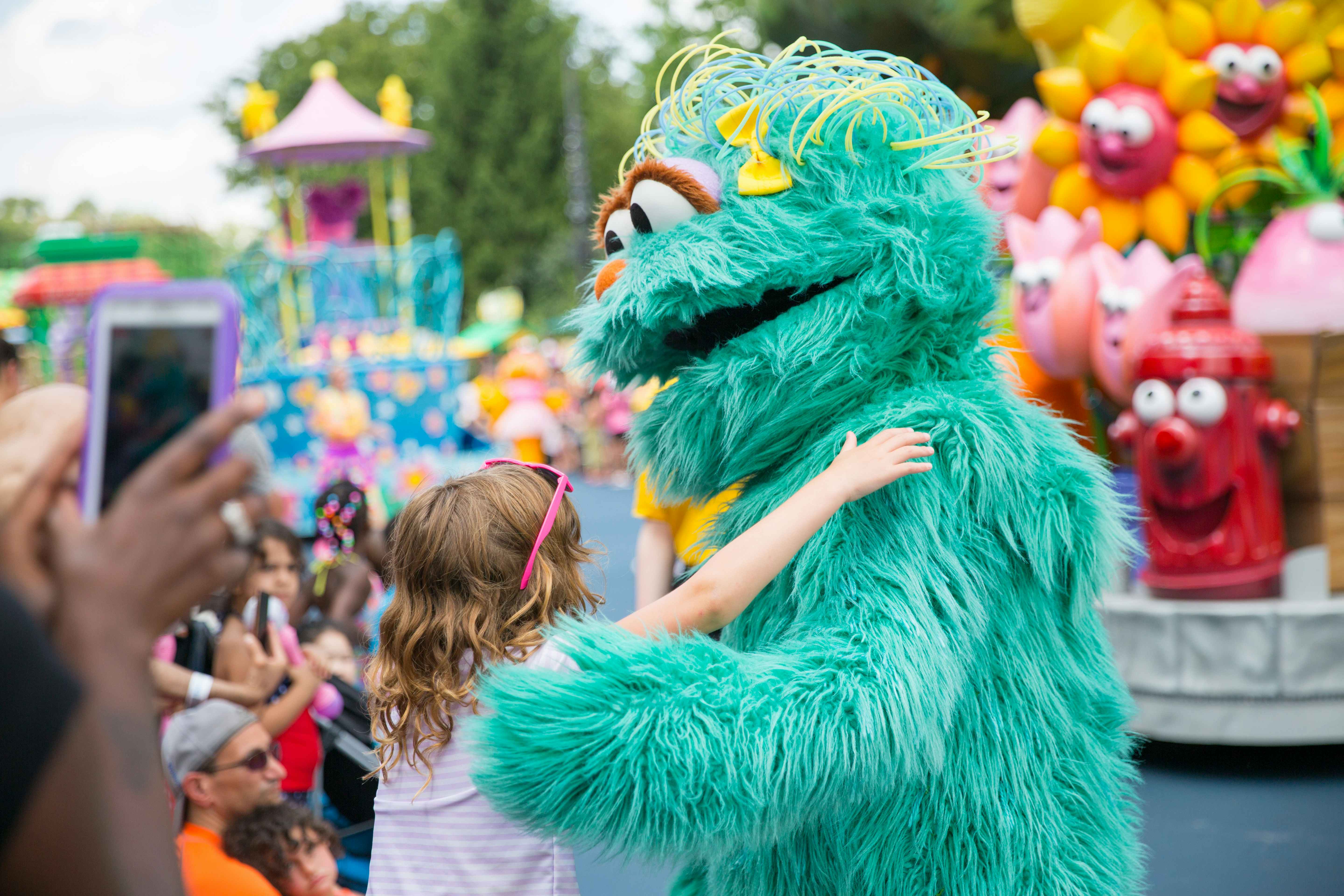 A child hugging a sesame street character at the Sesame Place parade in Philadelphia