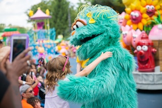 A child hugging a sesame street character at the Sesame Place parade in Philadelphia