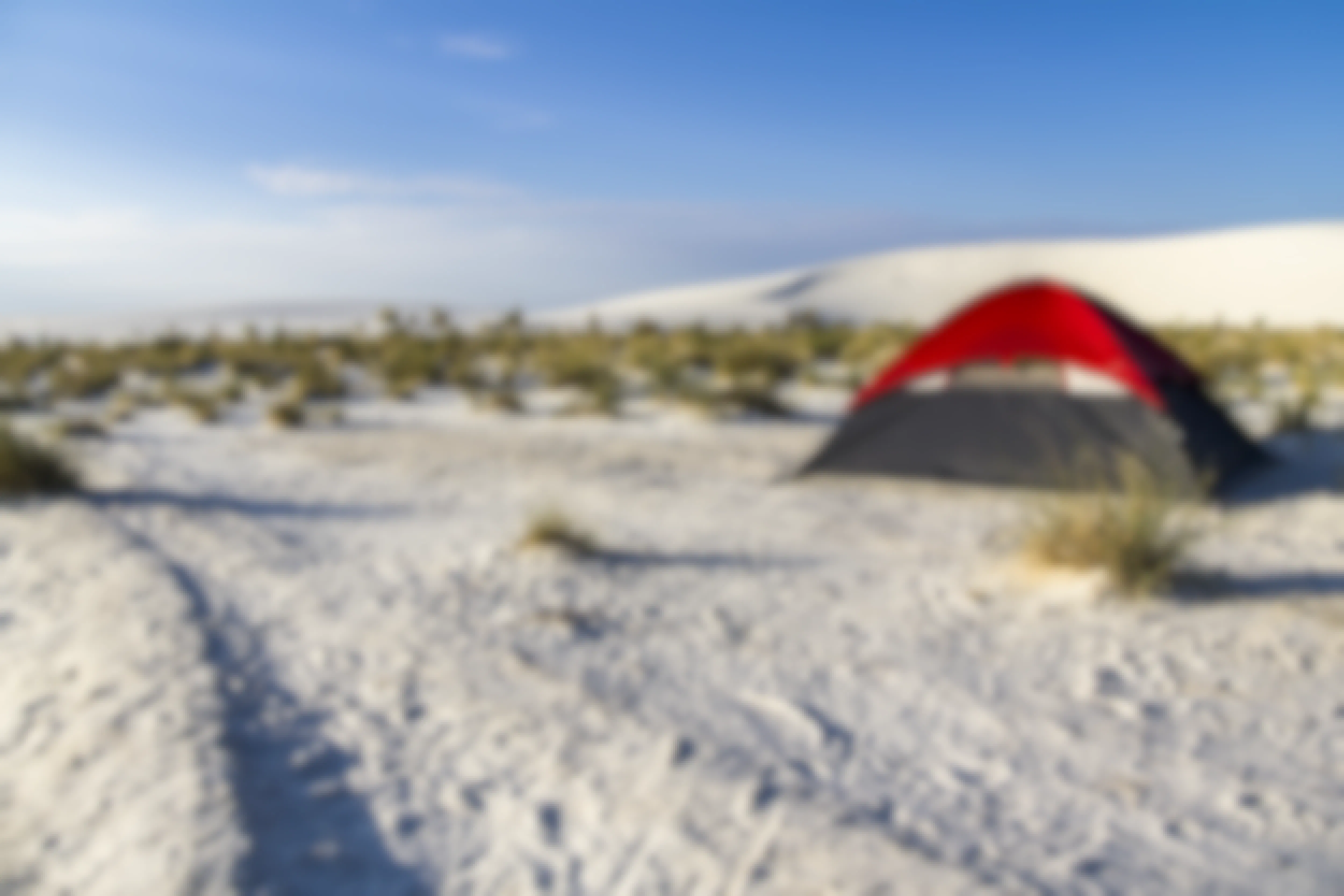 a red camping tent set up on a sandy plane in The White Sands National Park