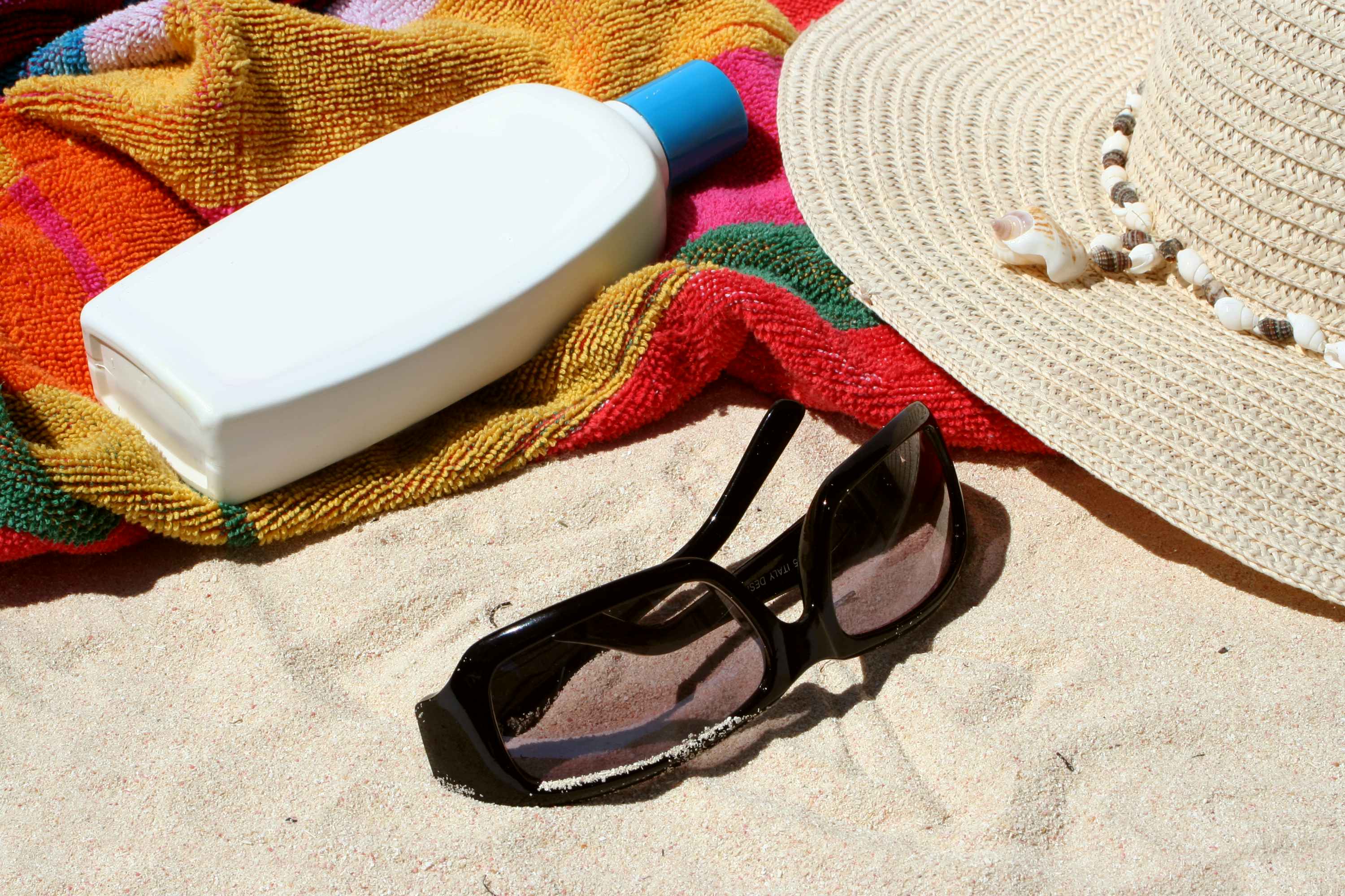 Sun block and sunglasses on a beach towel