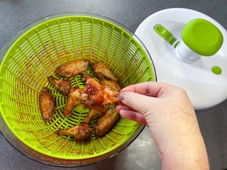 wings inside a salad spinner used to coat bbq sauce