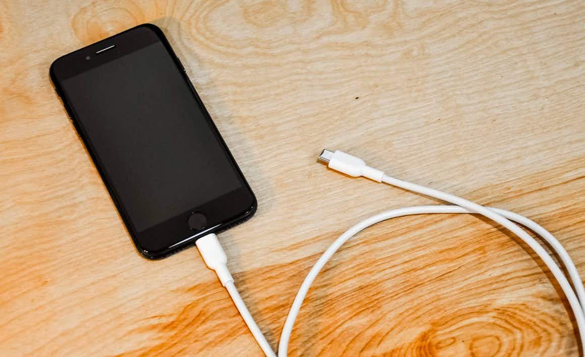 An iPhone plugged into a charging cord n a table