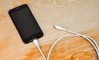 An iPhone plugged into a charging cord n a table