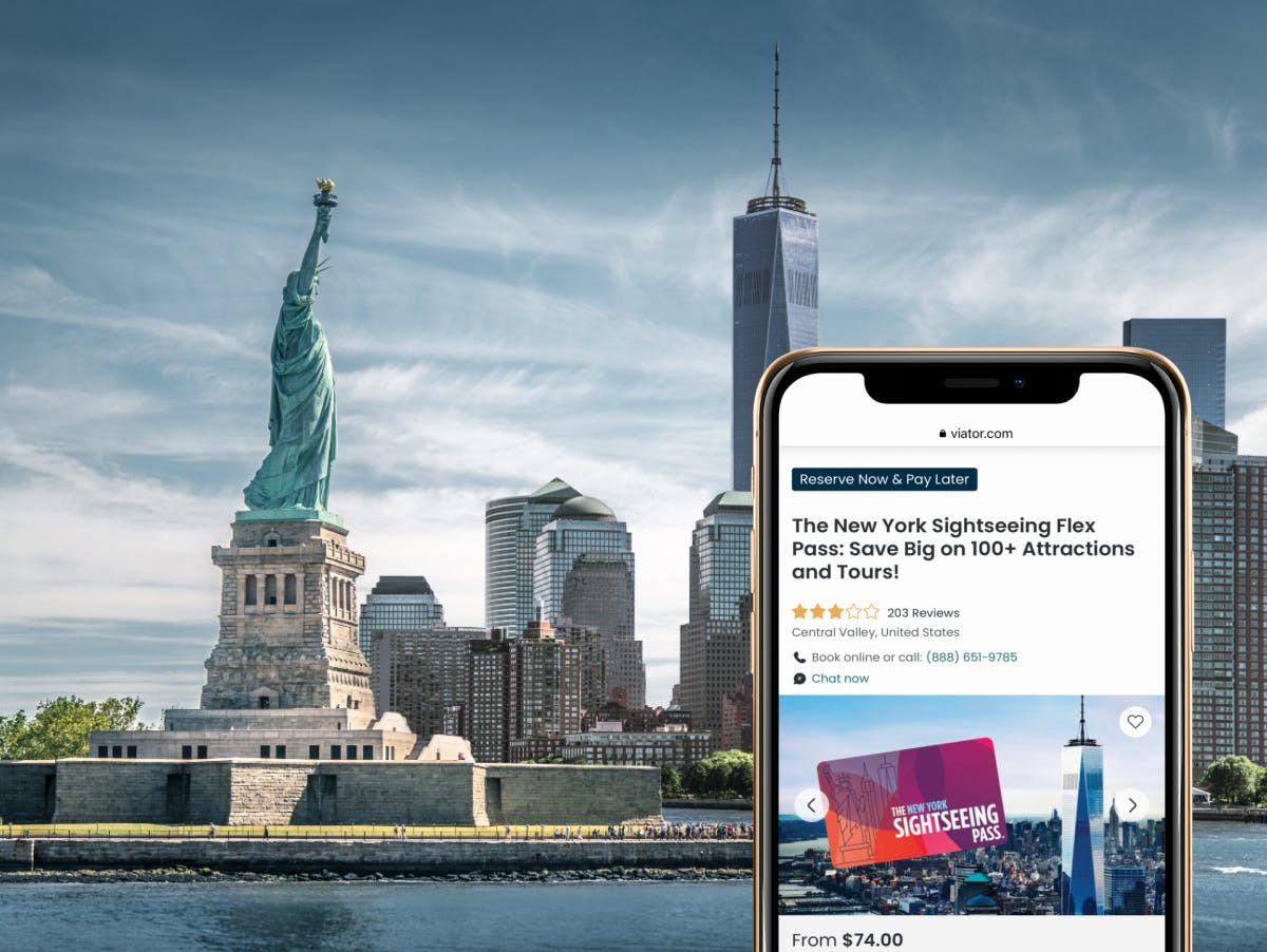 A view of the statue of liberty and downtown manhattan NYC behind a smartphone showing an NYC sightseeing pass on Viator.com