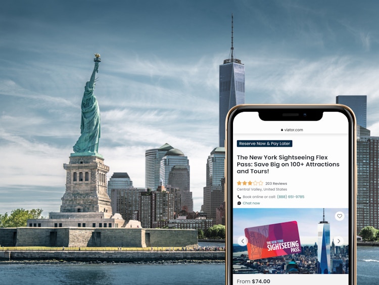 A view of the statue of liberty and downtown manhattan NYC behind a smartphone showing an NYC sightseeing pass on Viator.com