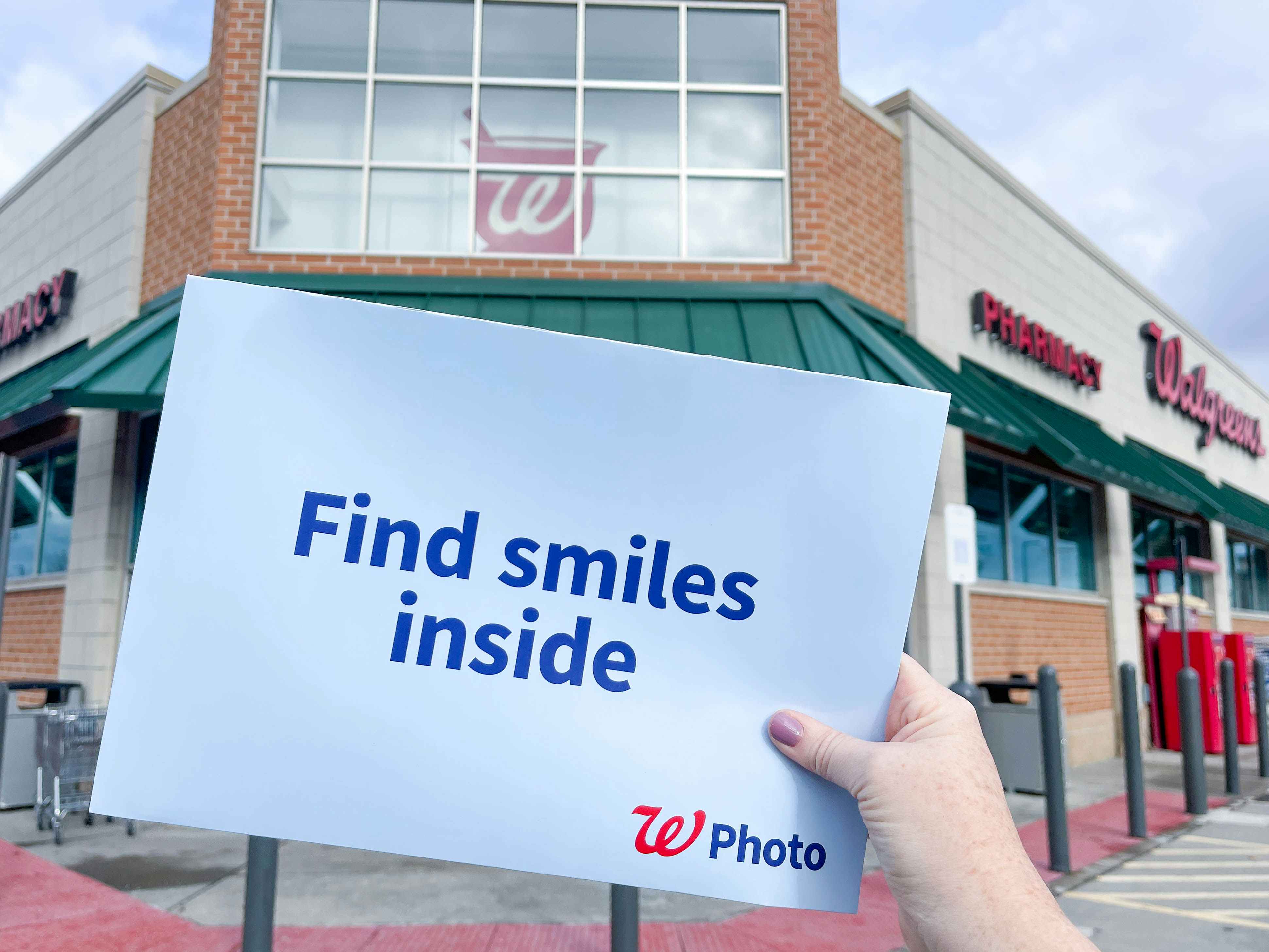 a person holding a photo prints package in hand in front of walgreens
