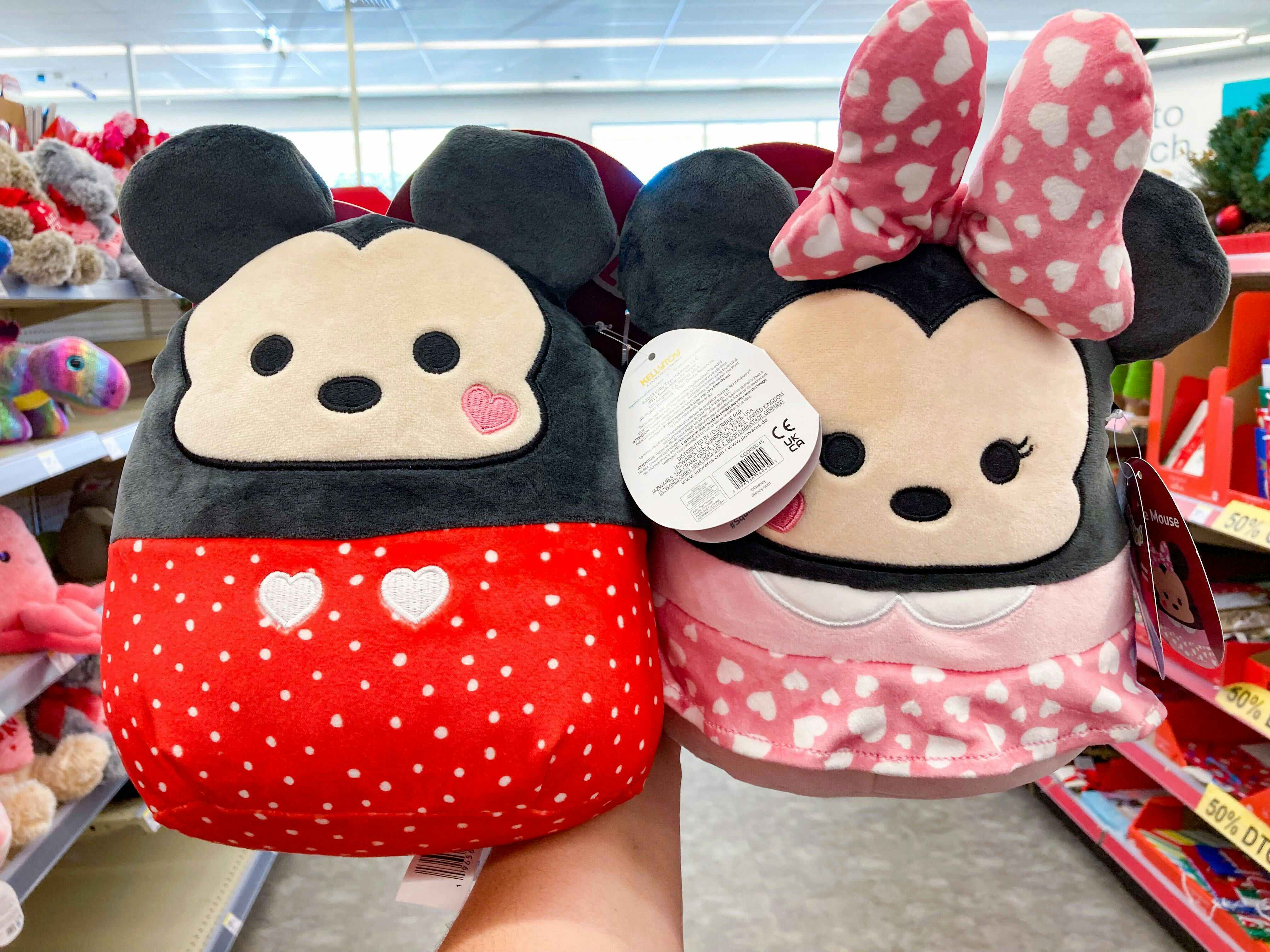 Someone holding up Mickey and Minnie Mouse Valentine's Day Squishmallows in Walgreens