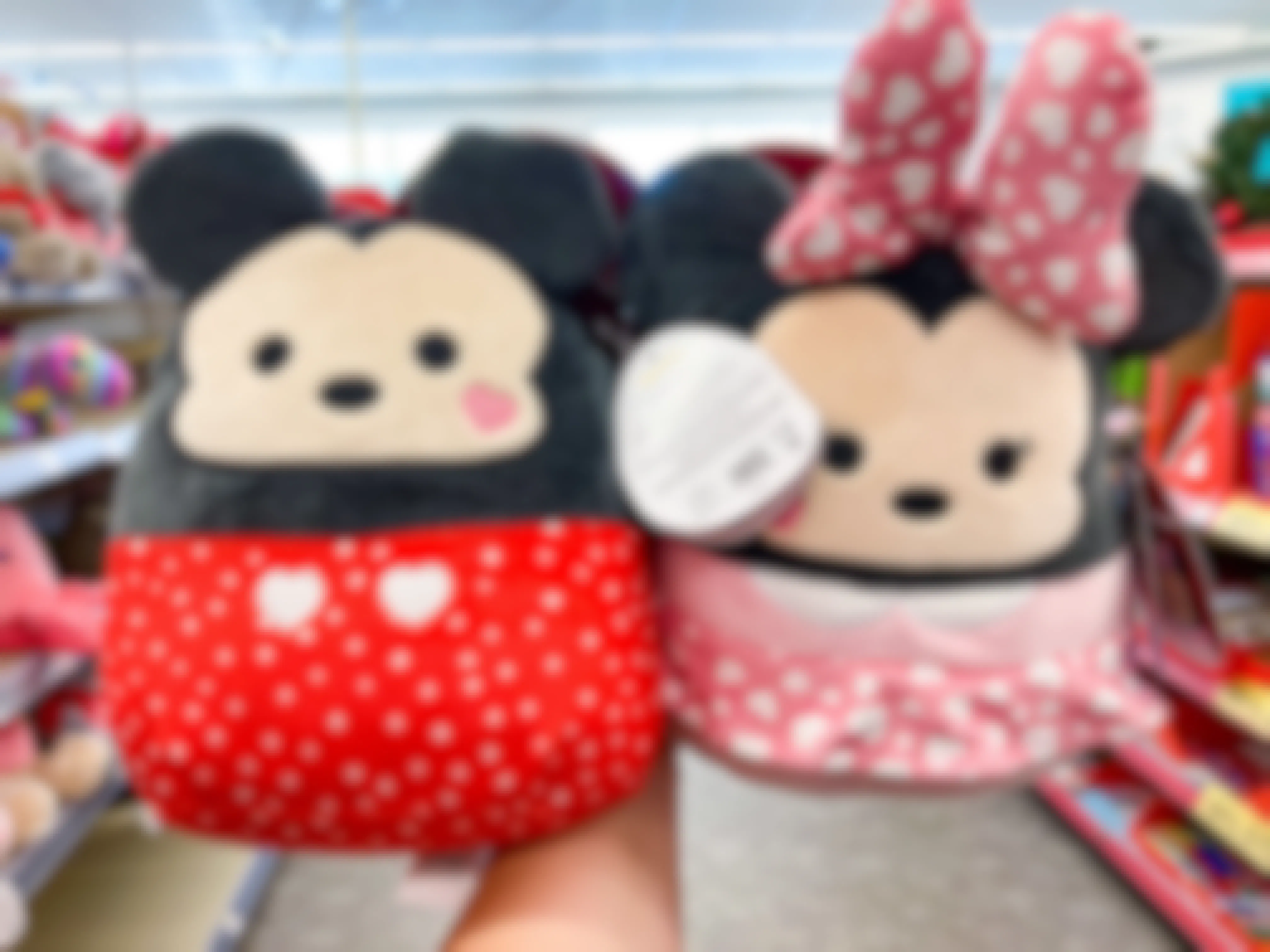 Someone holding up Mickey and Minnie Mouse Valentine's Day Squishmallows in Walgreens