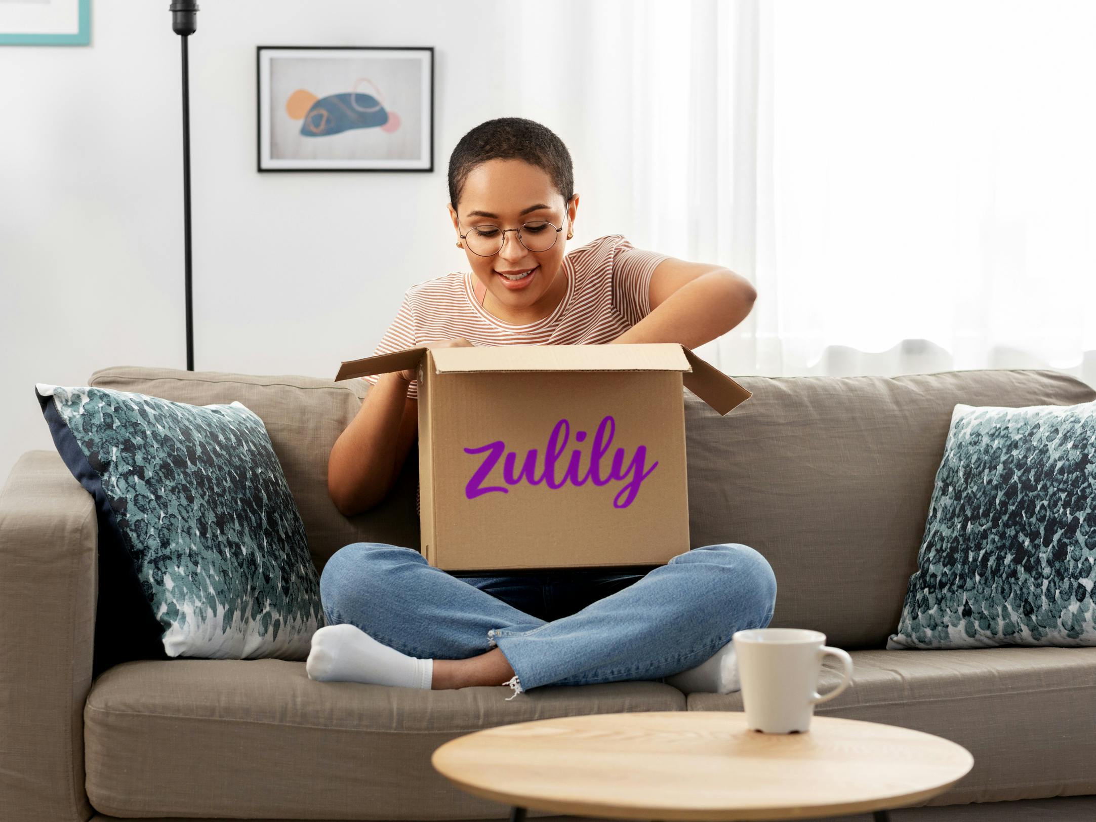 A person opening a Zulily box while sitting on a couch