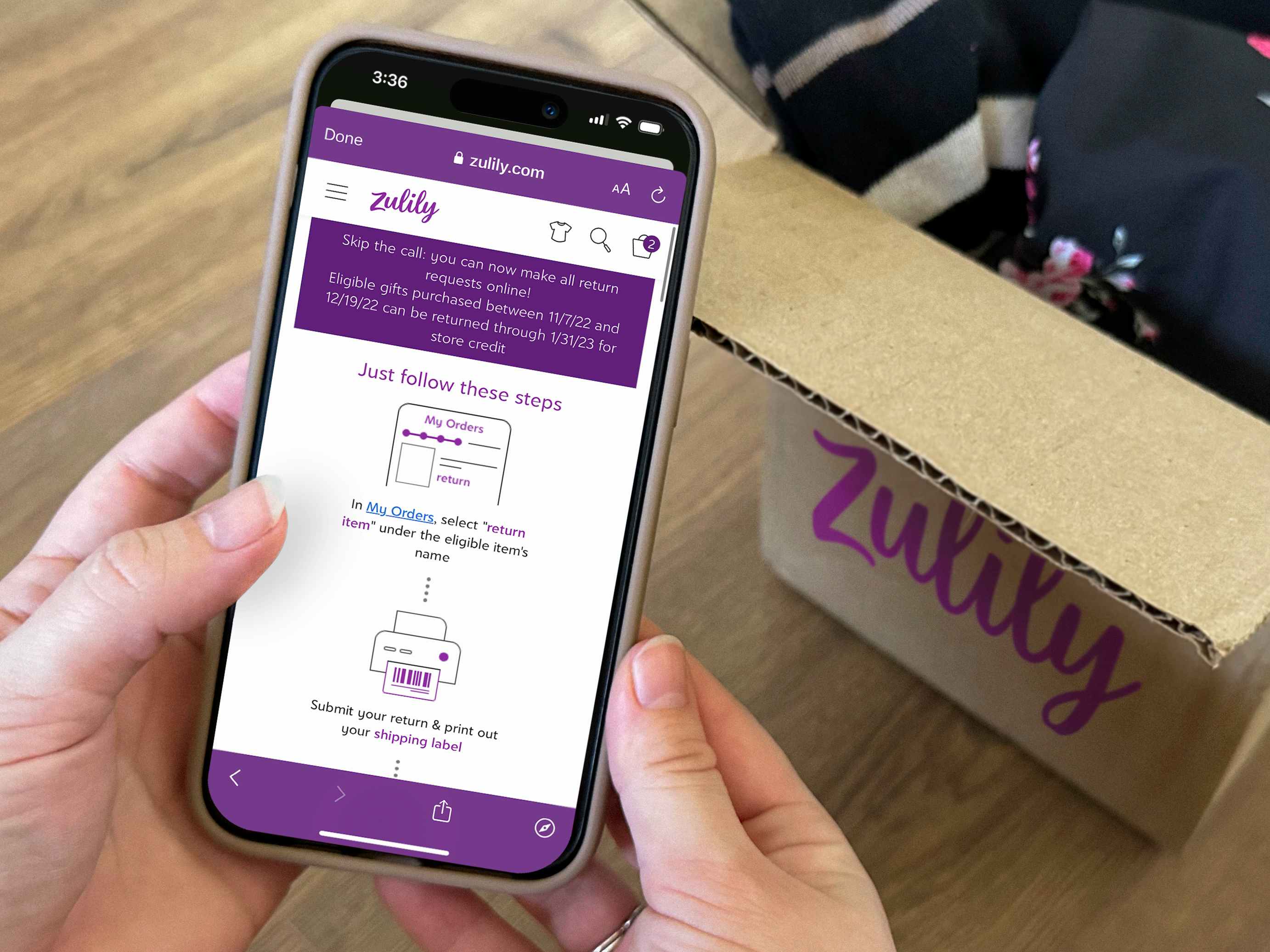 Someone looking up the Zulily return policy on their phone with an open Zulily box in the background