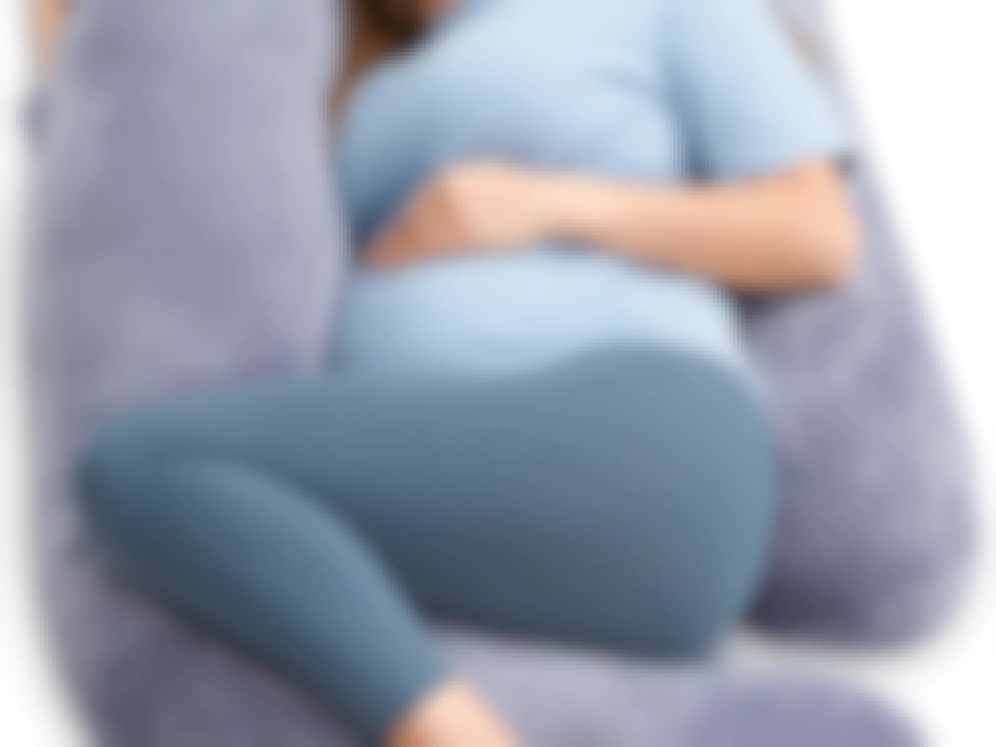 a pregnant person laying with a pregnancy pillow 