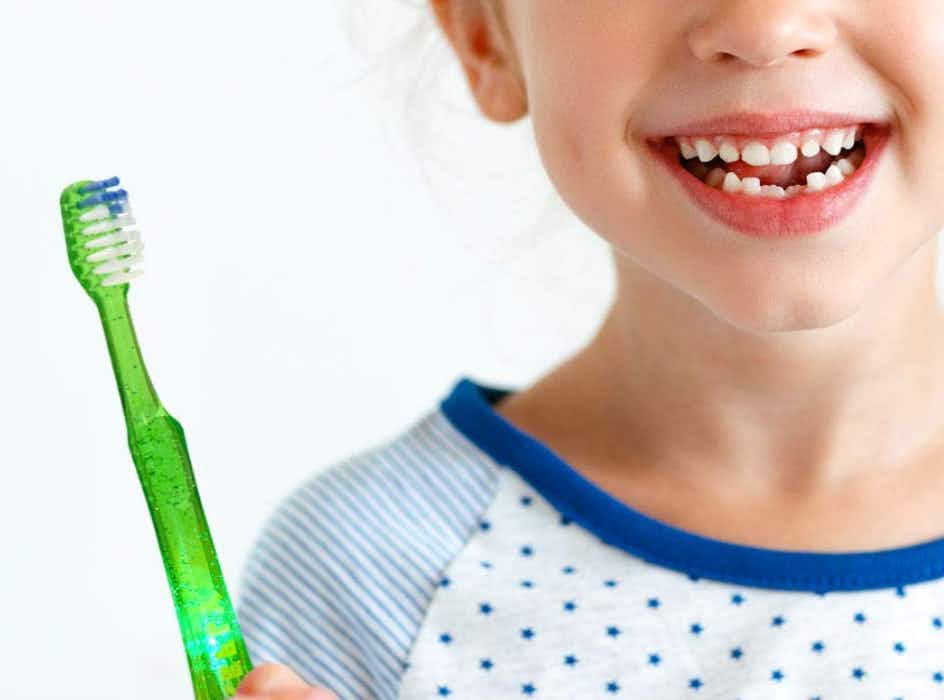 a kid holding a green toothbrush