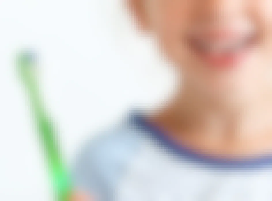 a kid holding a green toothbrush
