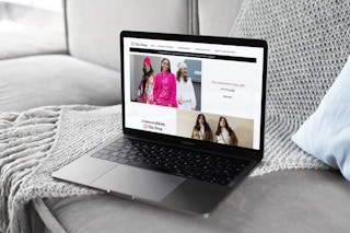 A laptop open on a gray sofa showing the homepage for The Drop on Amazon