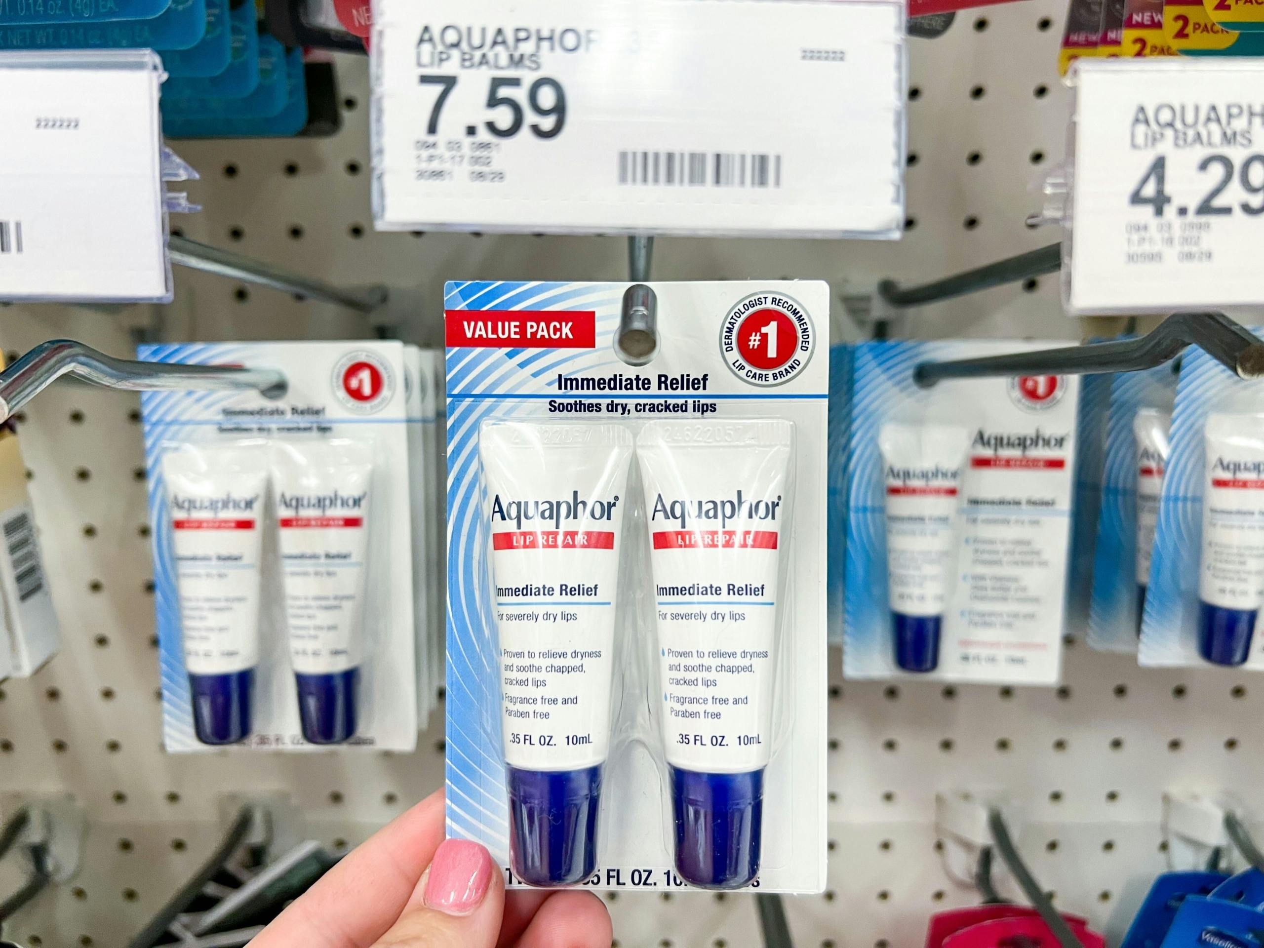 hand holding up two pack of Aquaphor lip balm inside Target in front of price tag