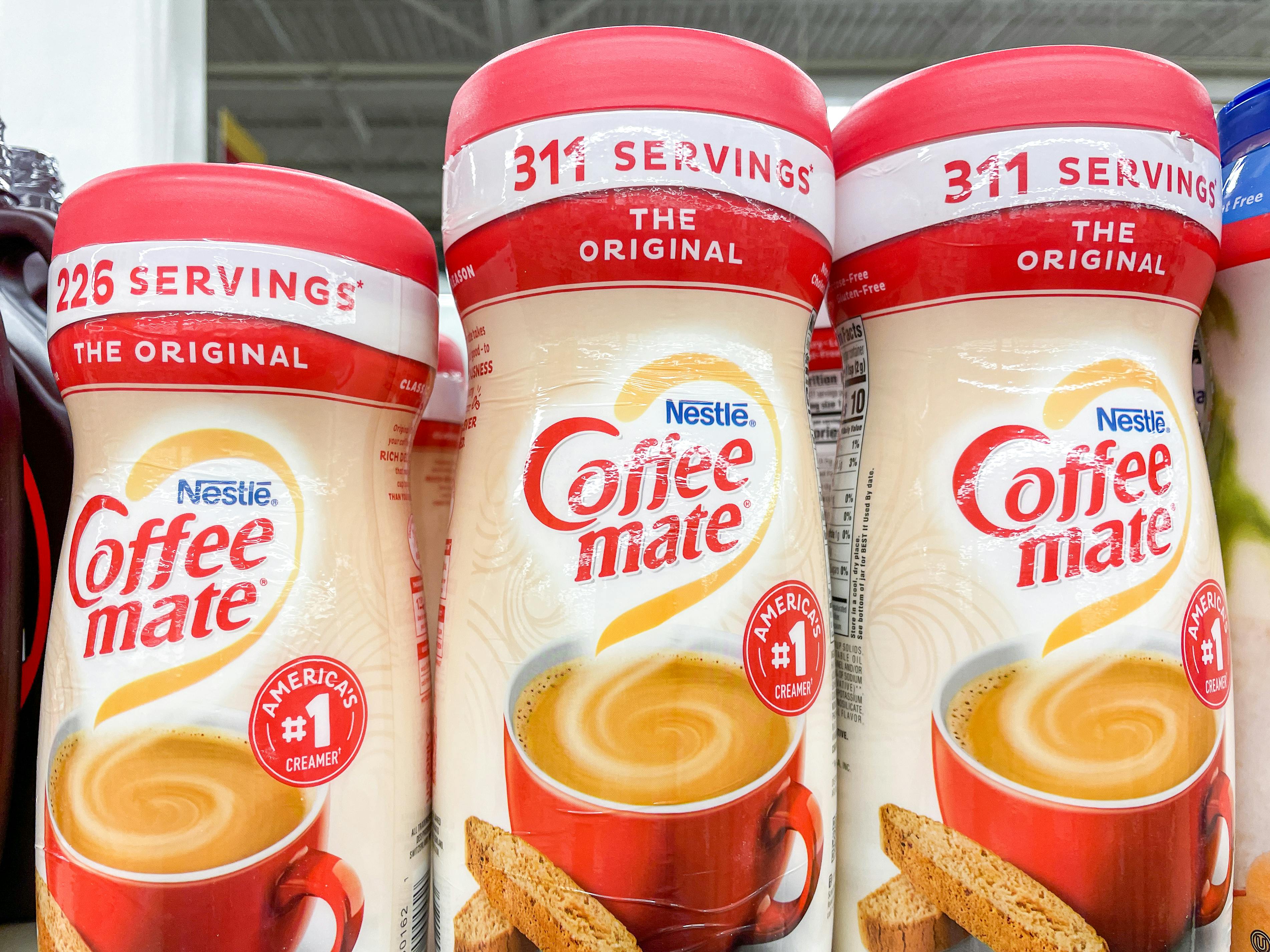 Containers of Coffee Mate powder creamer in a store showing the advertised serving sizes