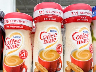 Containers of Coffee Mate powder creamer in a store showing the advertised serving sizes