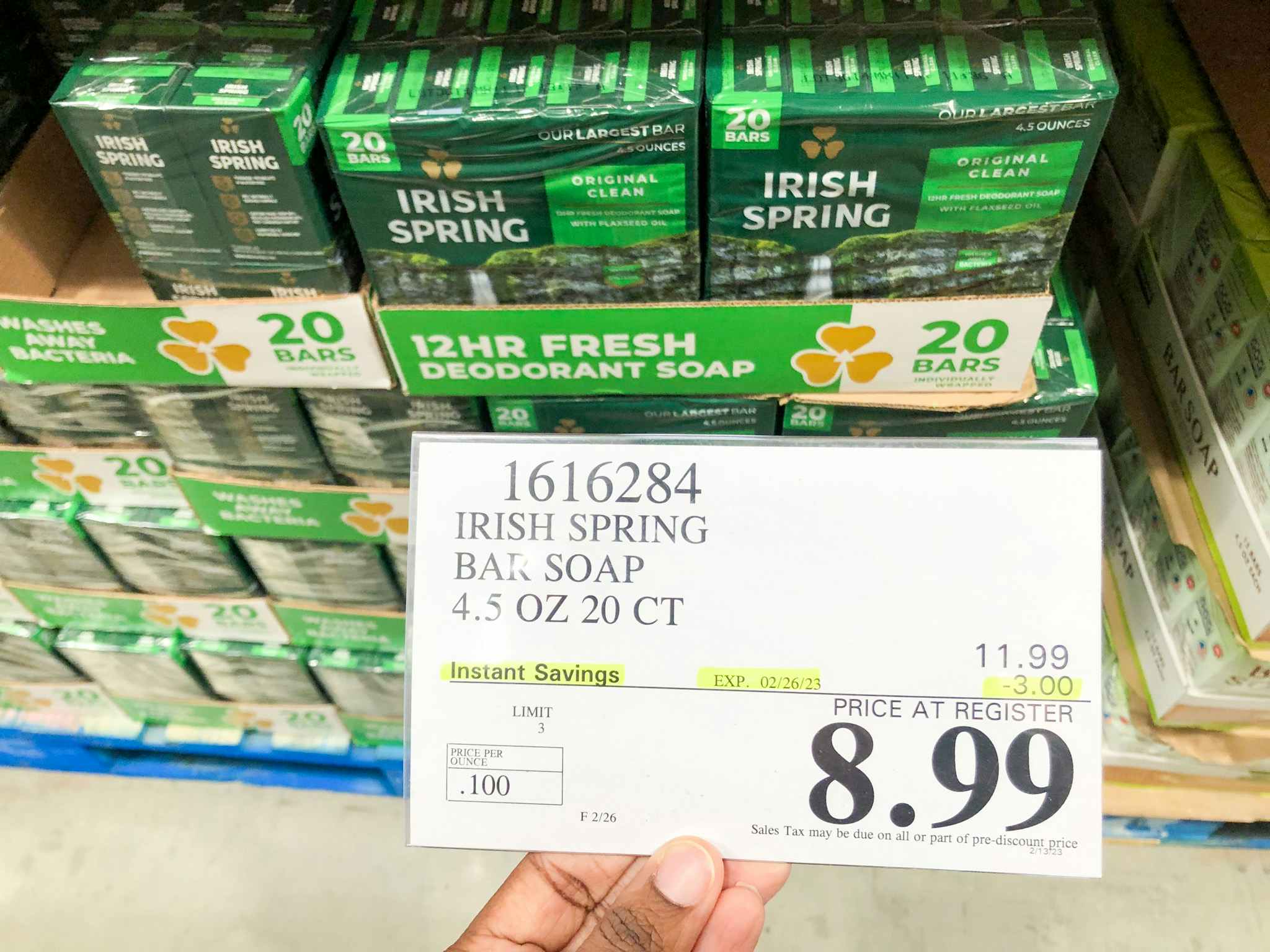 a person holding the price sign in costco in front of irish spring soap 