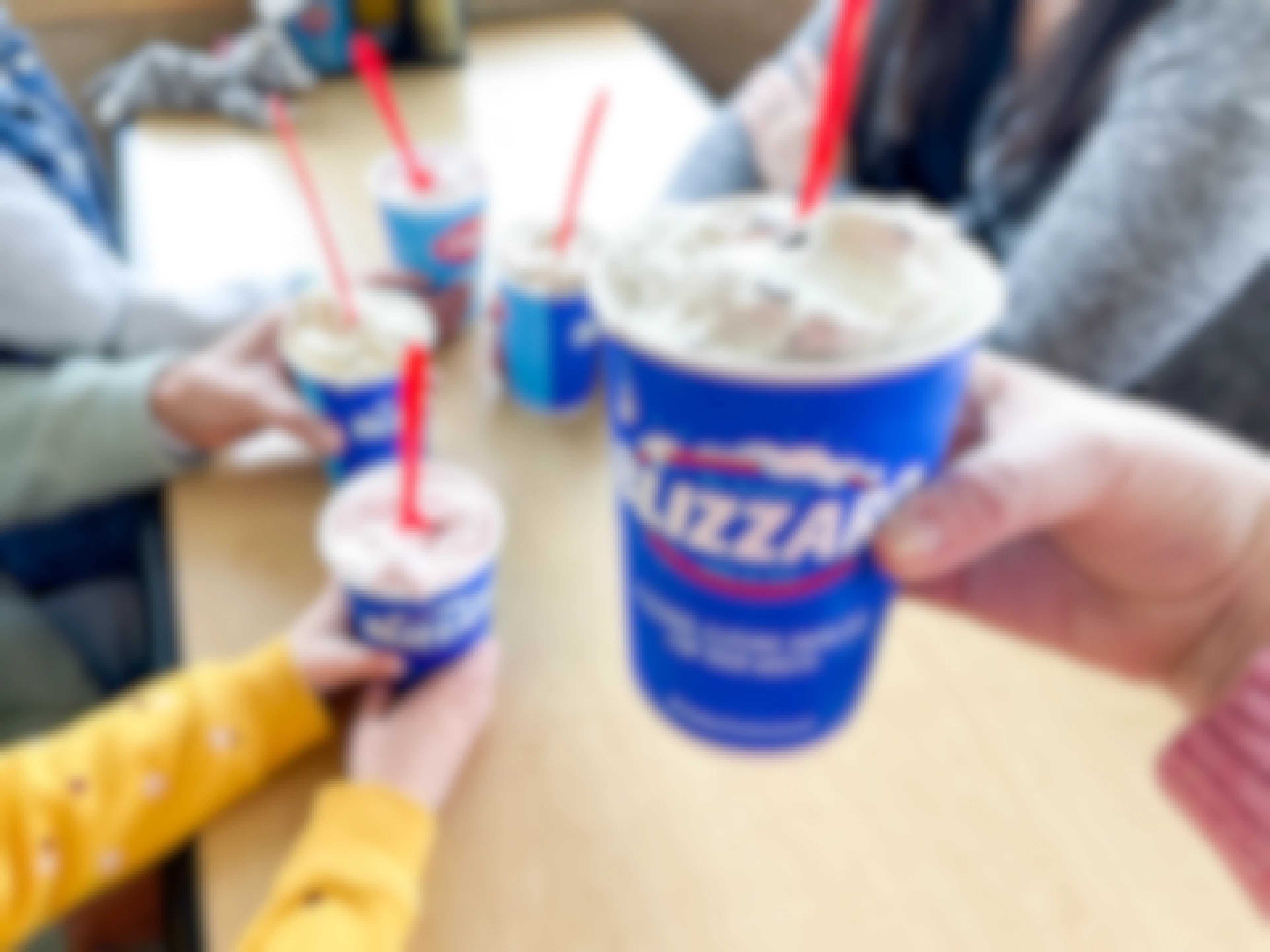 a person holding a dairy queen blizzard in front of a table of people having blizzards 