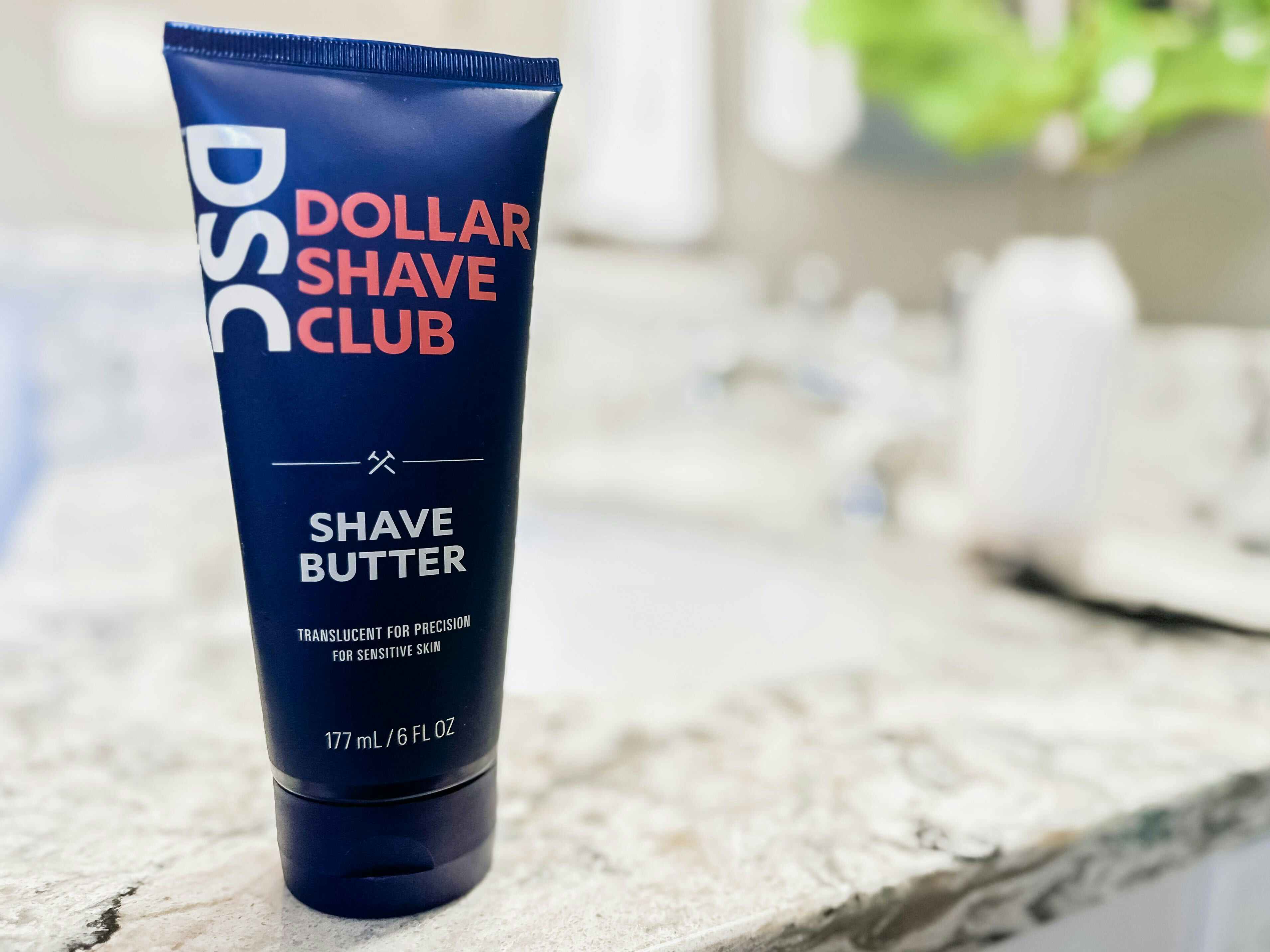 A bottle of the Dollar Shave Club Shave Butter on a bathroom countertop