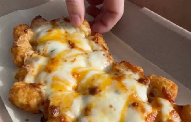 a hand reaching for the dominos loaded tots