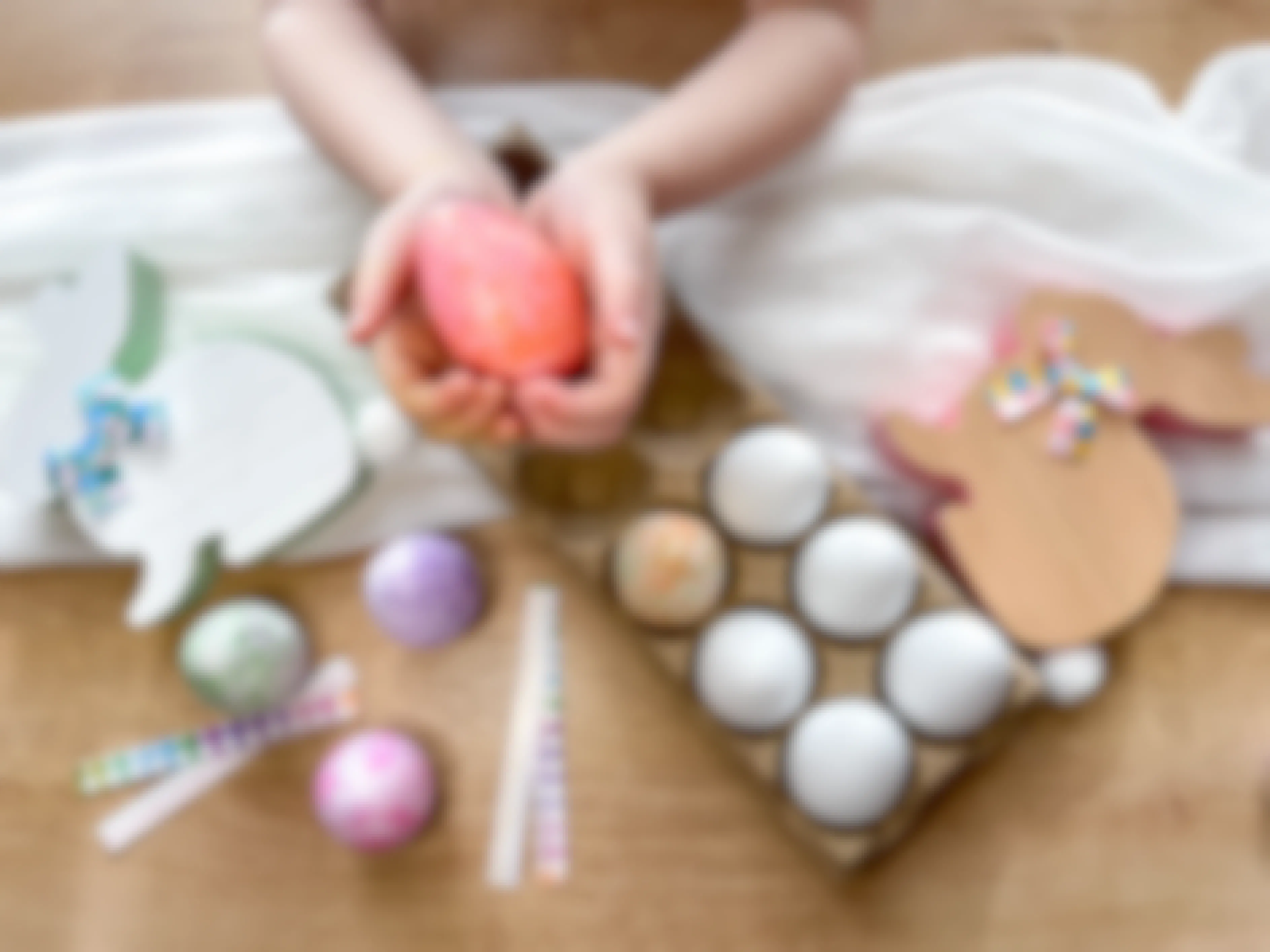 a kid holding a dyed egg near other plastic eggs and easter decor
