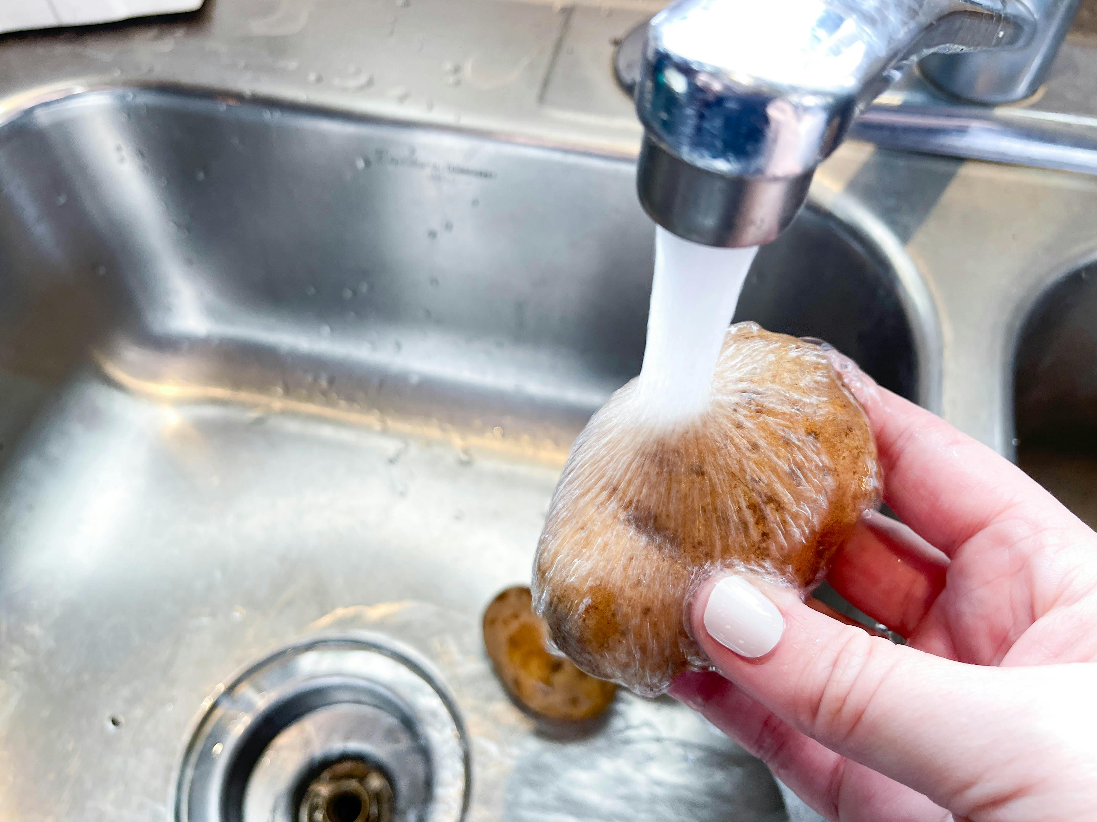 washing a potato in the sink 
