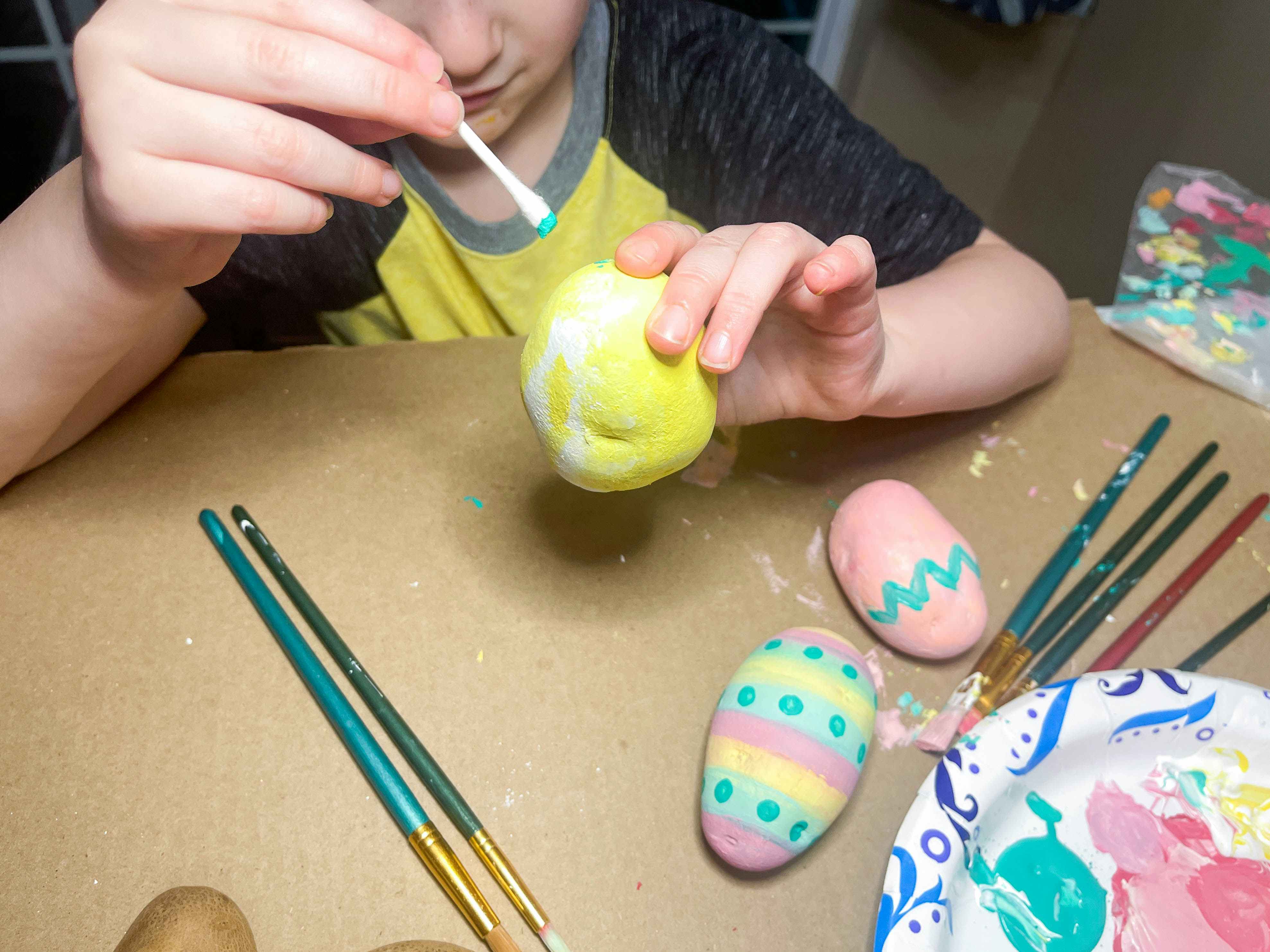 a little kid painting a potato with qtip 