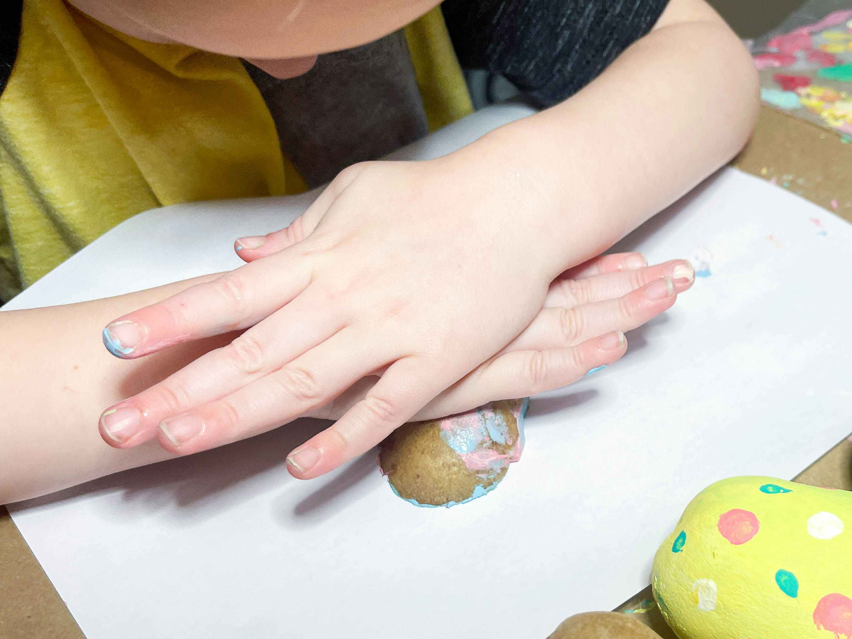 a kid pressing a painted potato stamp