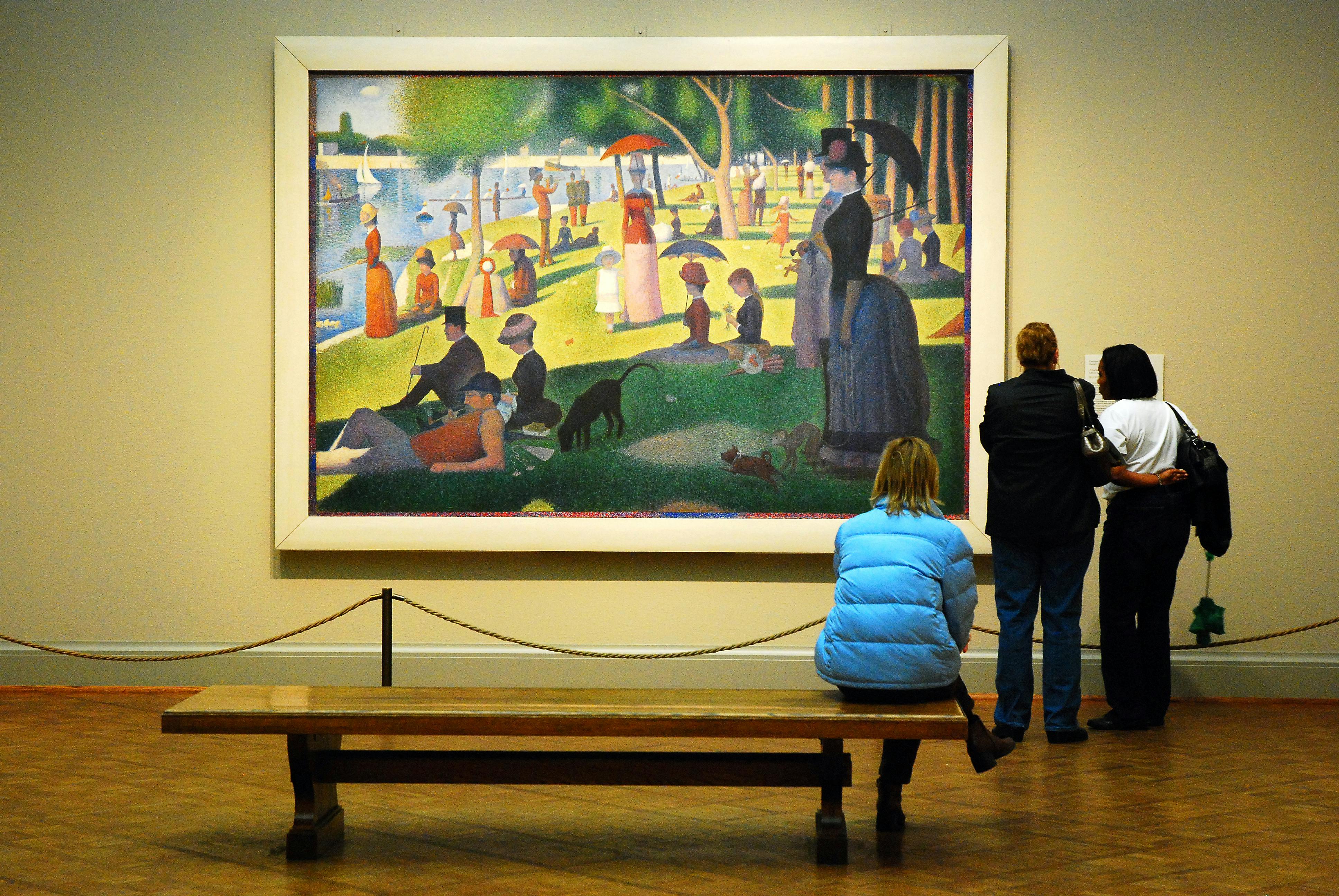 People looking at a Georges Seurat painting in an exhibit at the Art Institute of Chicago