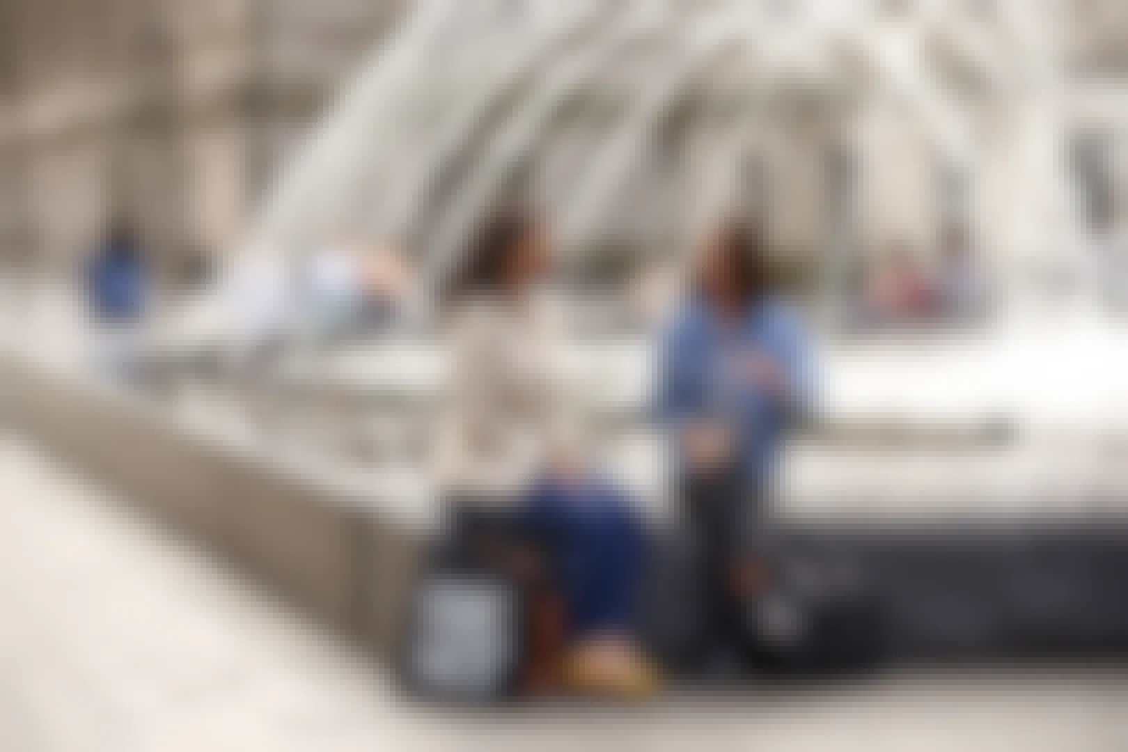 Two people having a conversation while sitting on a fountain outside of The Metropolitan Museum of Art with bags that say "The Met