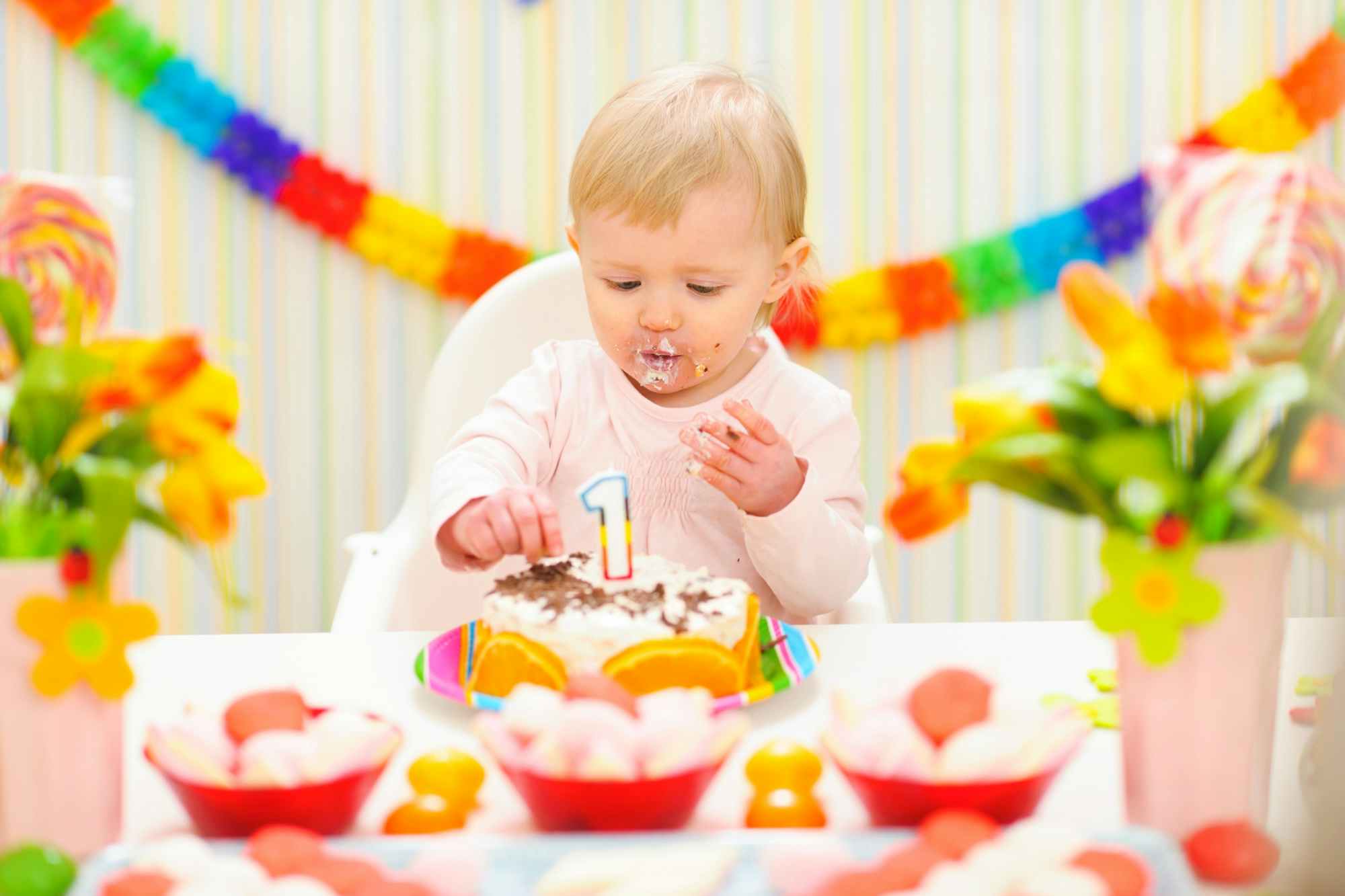A baby digging into a cake with their hands