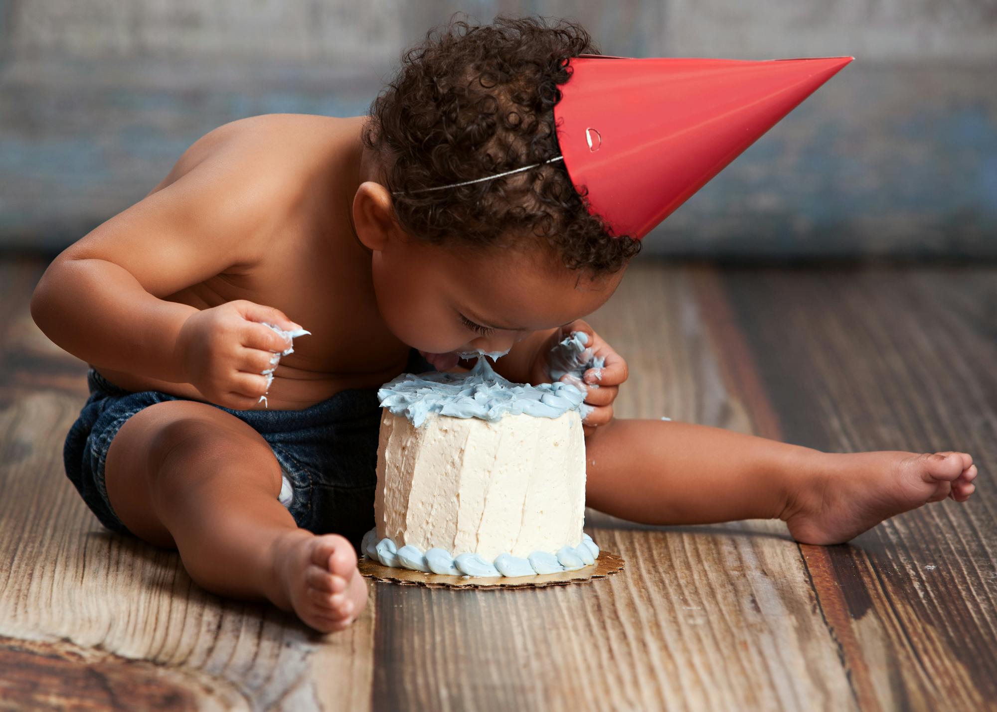 A baby sticking his face into a small birthday cake