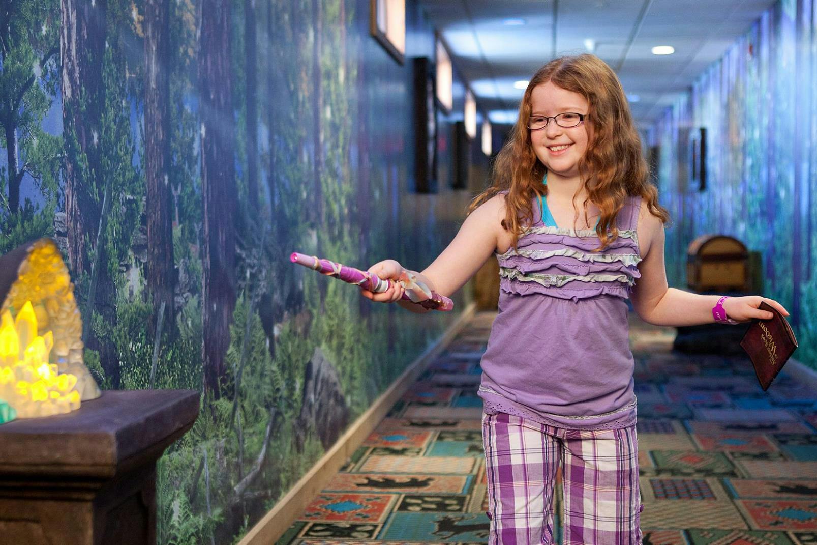 A kid pointing a wand at a Magiquest object in Great Wolf Lodge