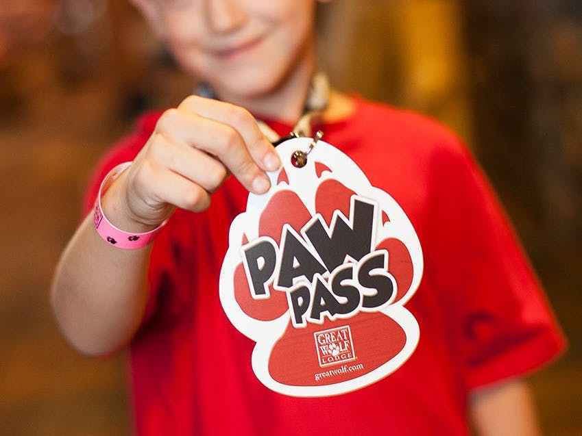 A child holding up a Great Wolf Lodge Paw Pass