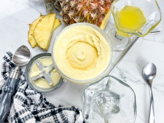 homemade doloe whip on a counter with ice cream cups and a pineapple