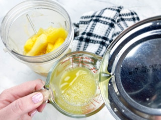 a person pouring canned pineapple juice into a measuring cup