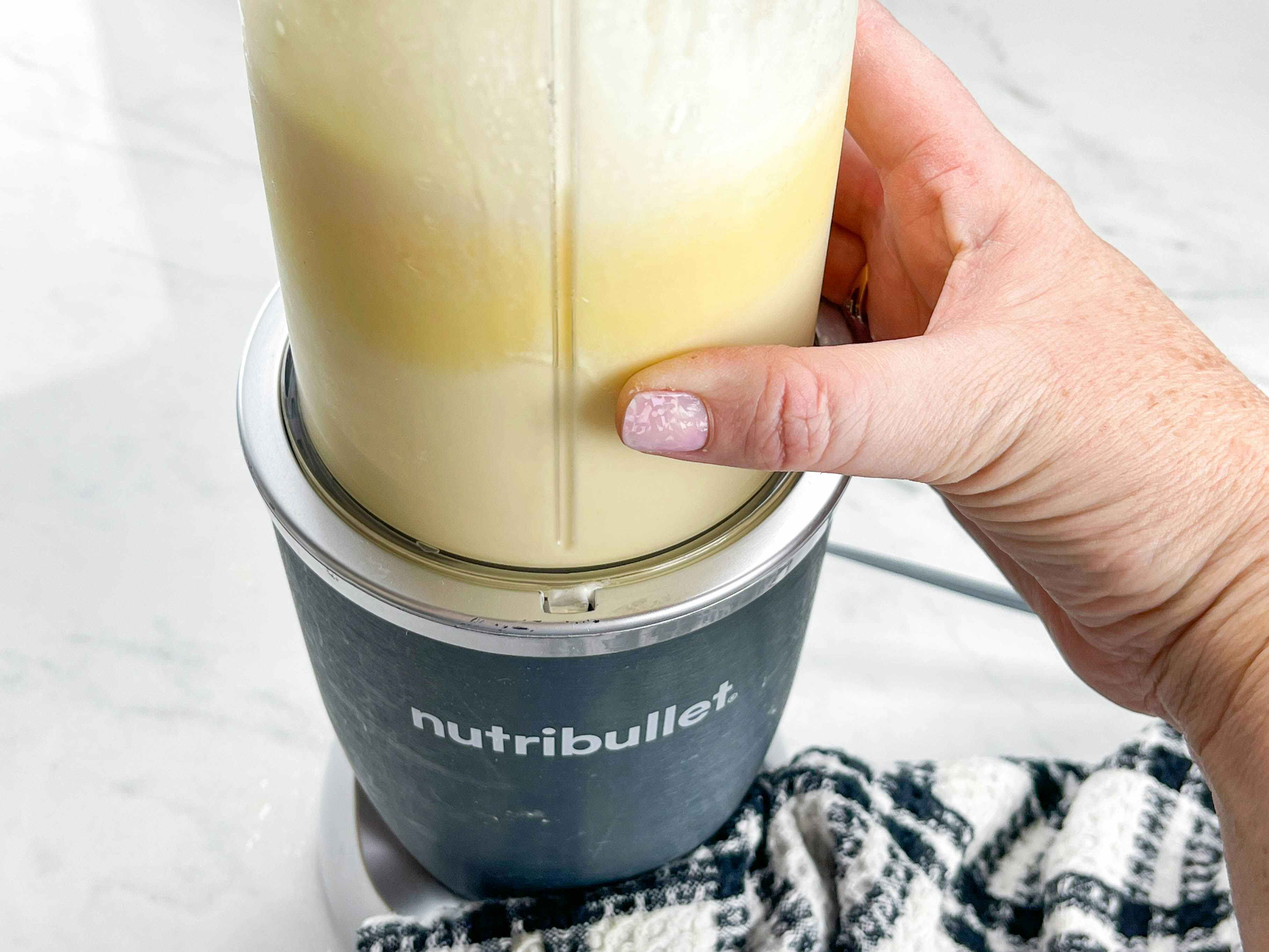 a person using a nutribullet blender to mix homemade dole whip 