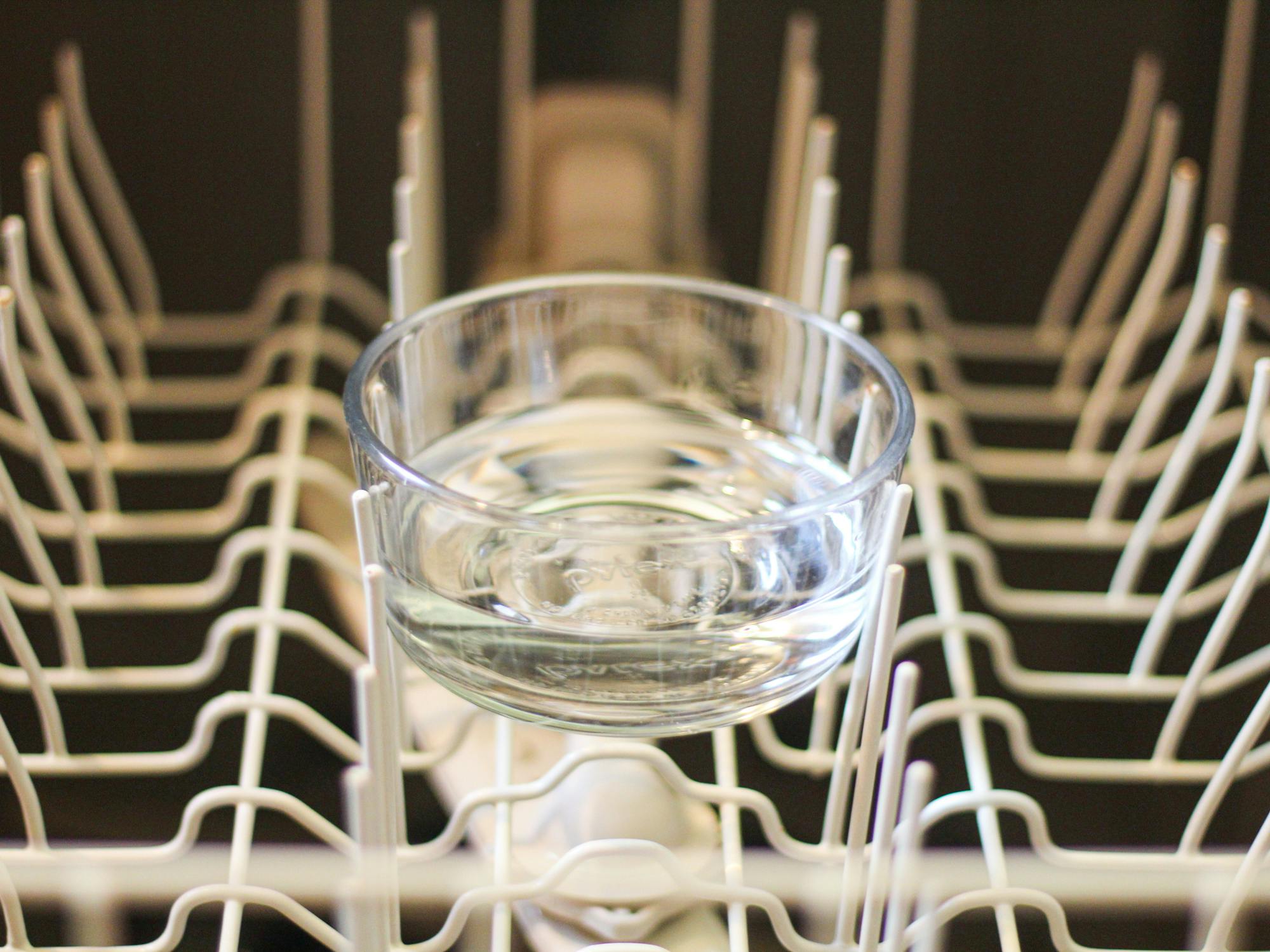 a dishwasher safe bowl filled with vinegar sitting on the top rack of a dishwasher