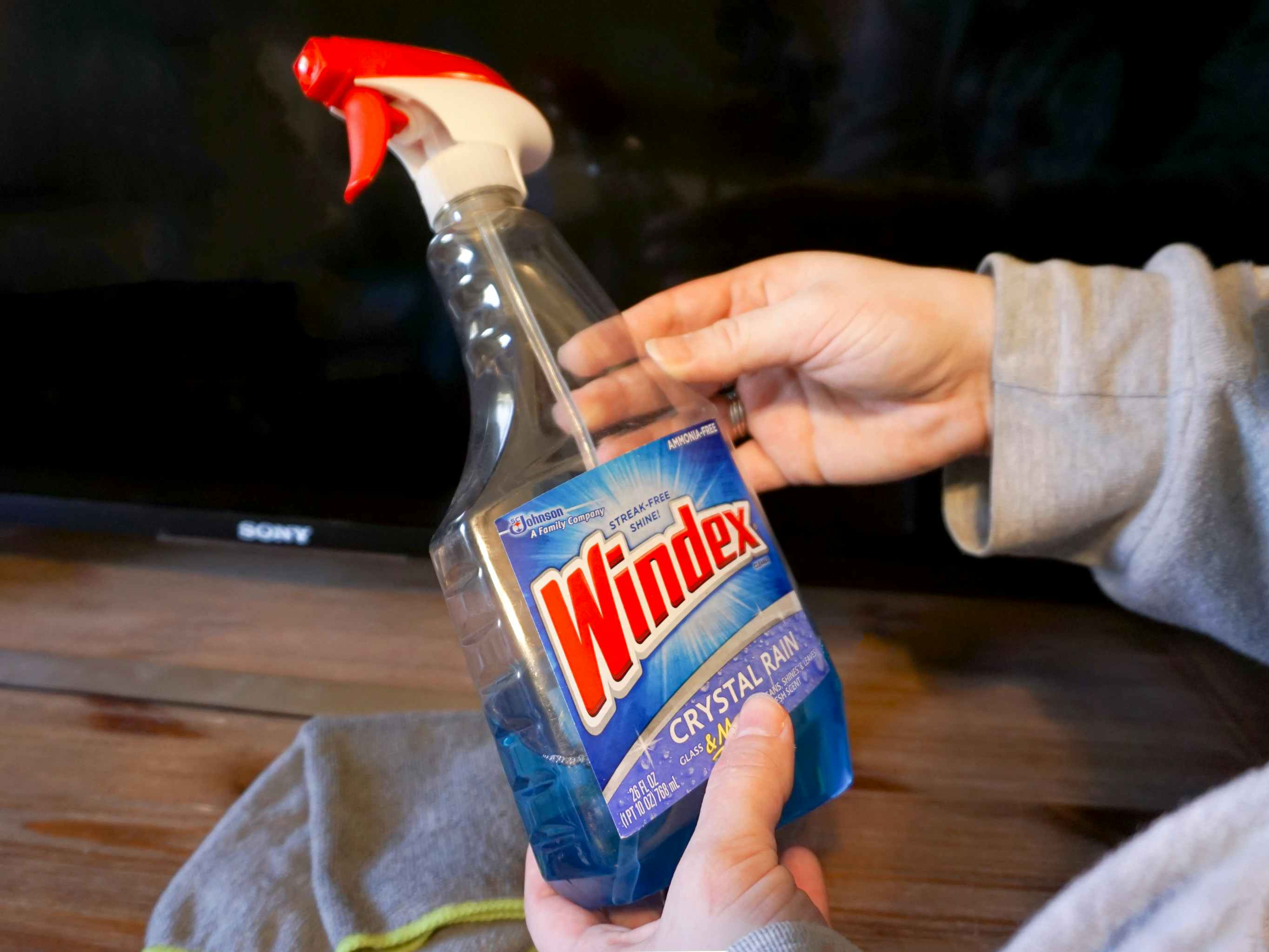 Someone holding a bottle of Windex in front of their TV