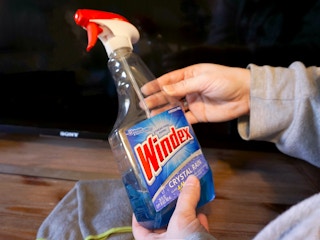 Someone holding a bottle of Windex in front of their TV
